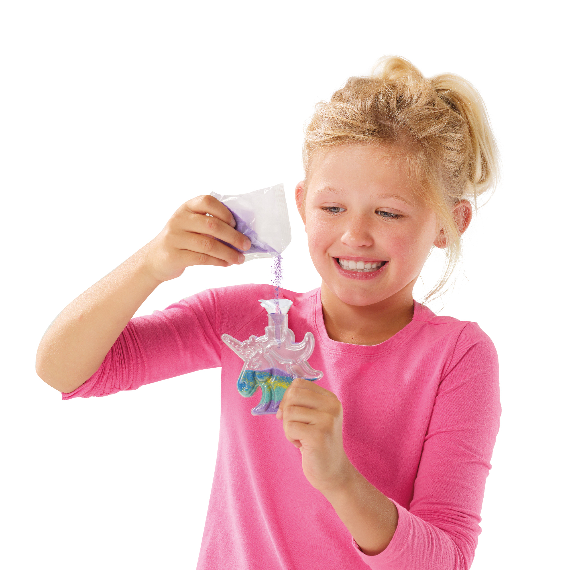 Dziewczyna wsypuje fioletowy piasek do pojemnika w kształcie jednorożca, uśmiechając się.