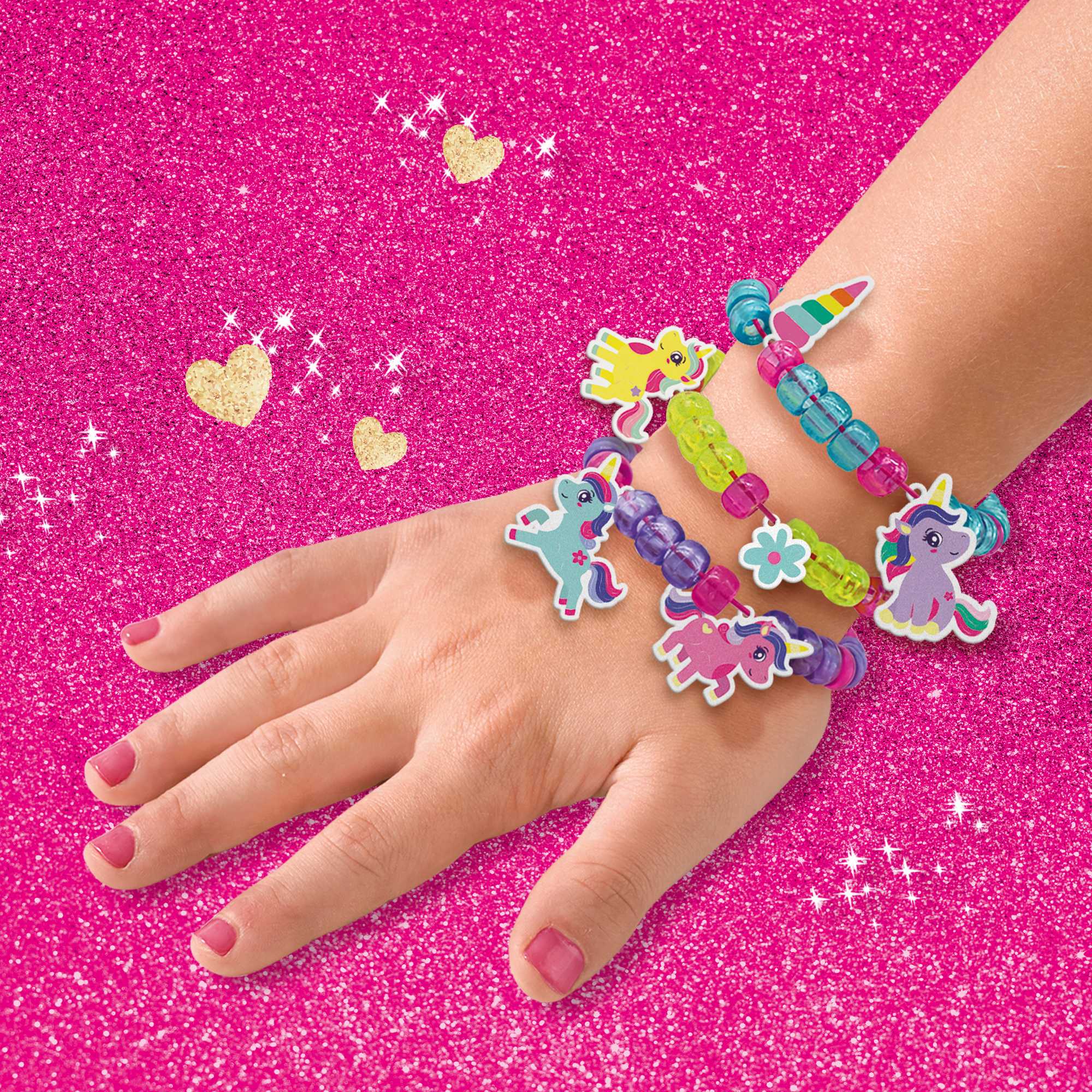 Una mano con diversi braccialetti a tema unicorno. I braccialetti sono di vari colori e presentano ciondoli a forma di unicorno.