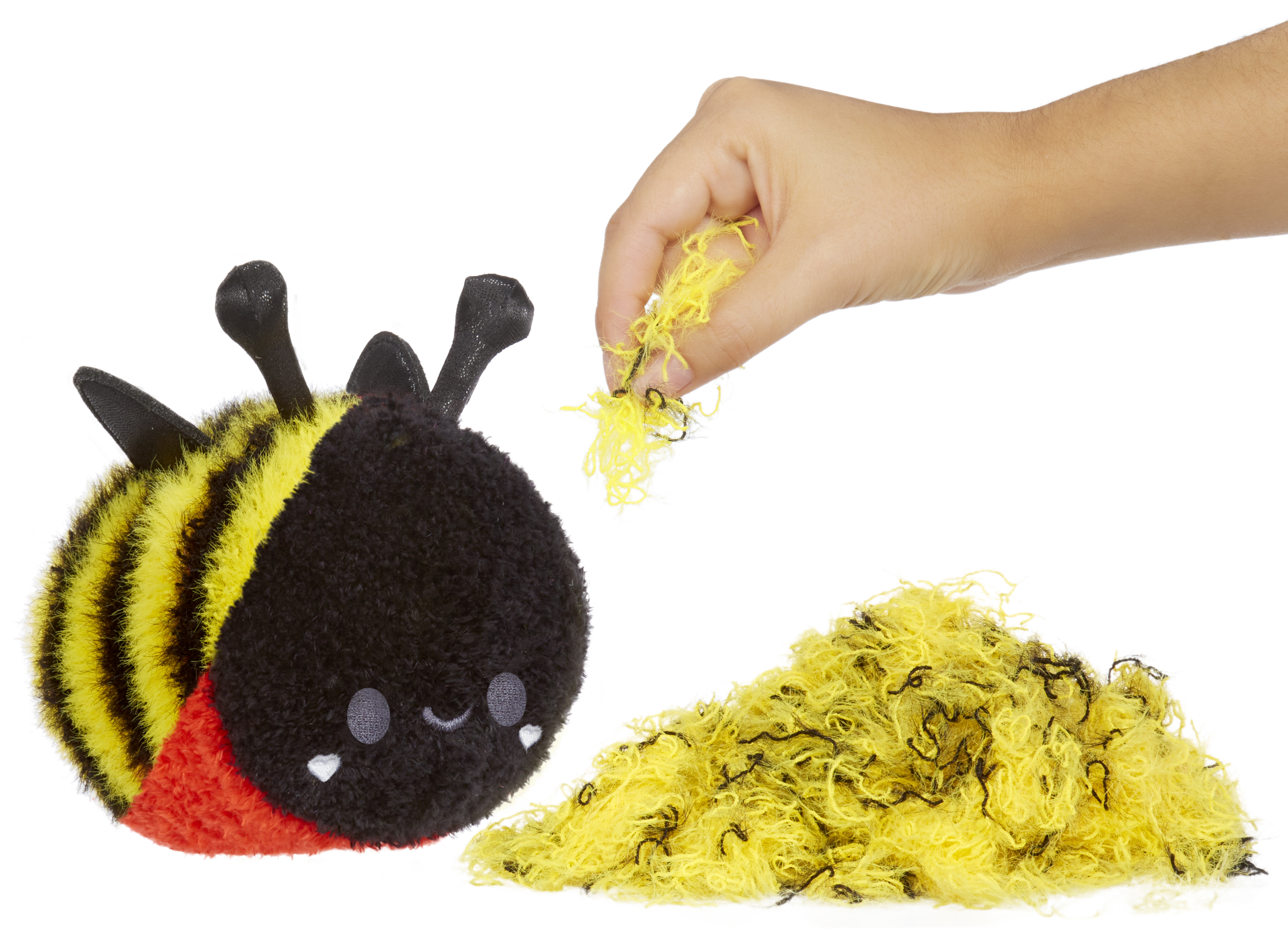 Mano che tira lanugine gialla da un peluche a forma di ape, sfondo bianco.