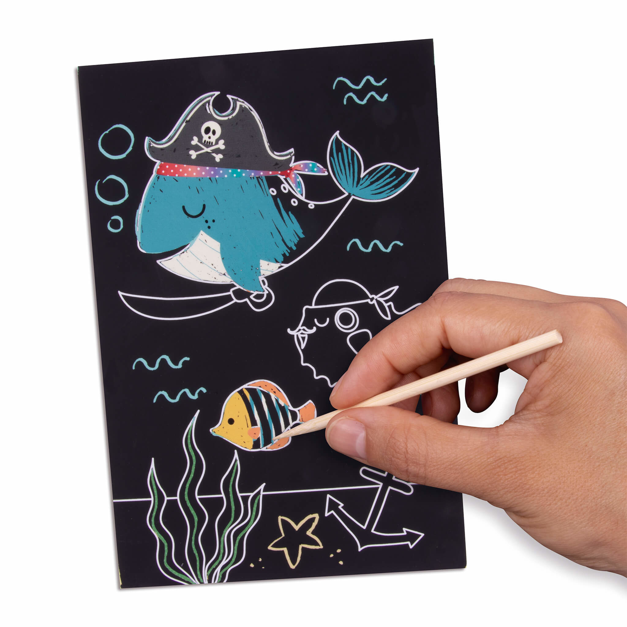 Eine Hand kratzt eine schwarze Karte mit einem Piratenwal, Fisch und Ankern.