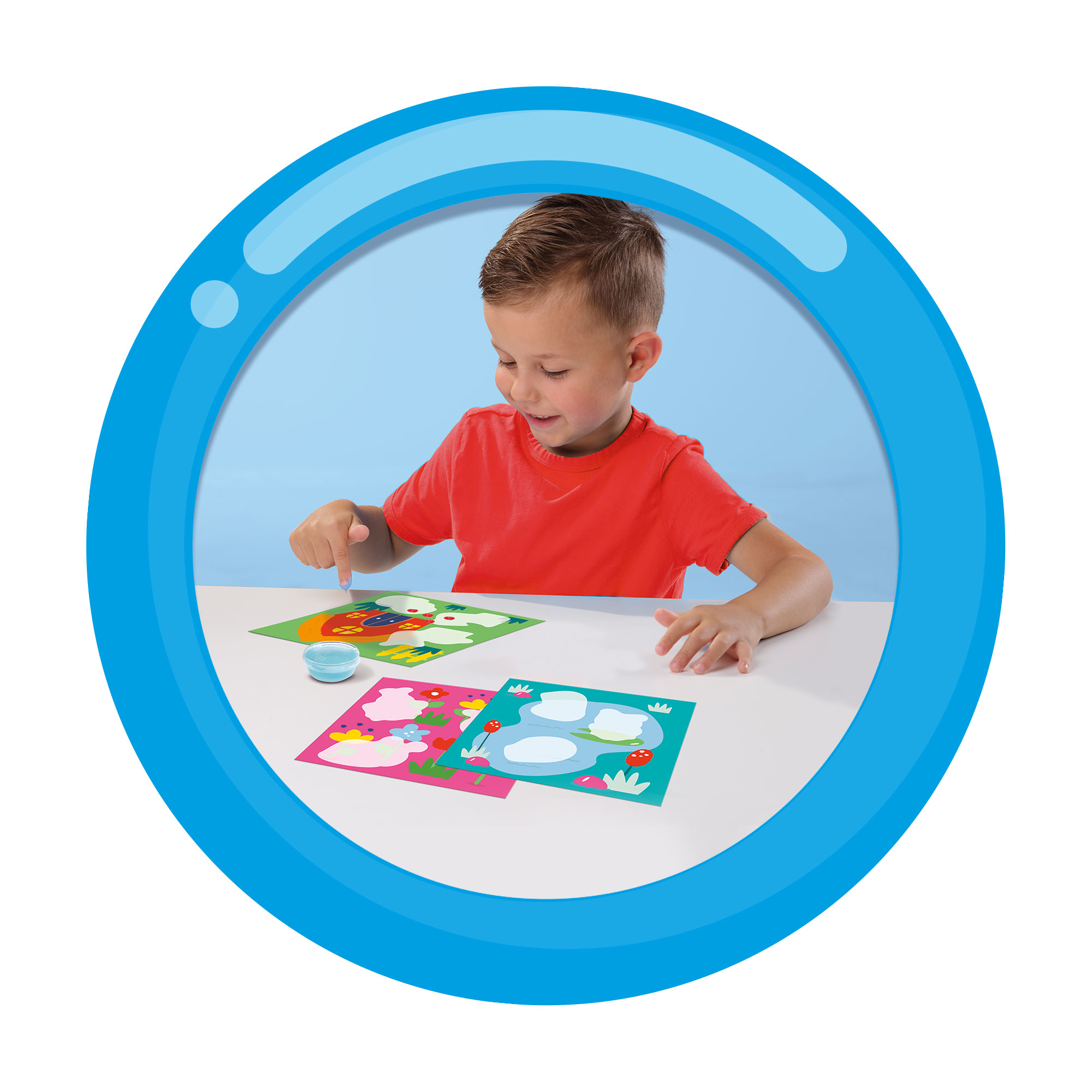 Chłopiec w niebieskim kole bawi się dwoma małymi, kolorowymi rysunkami na białej powierzchni.