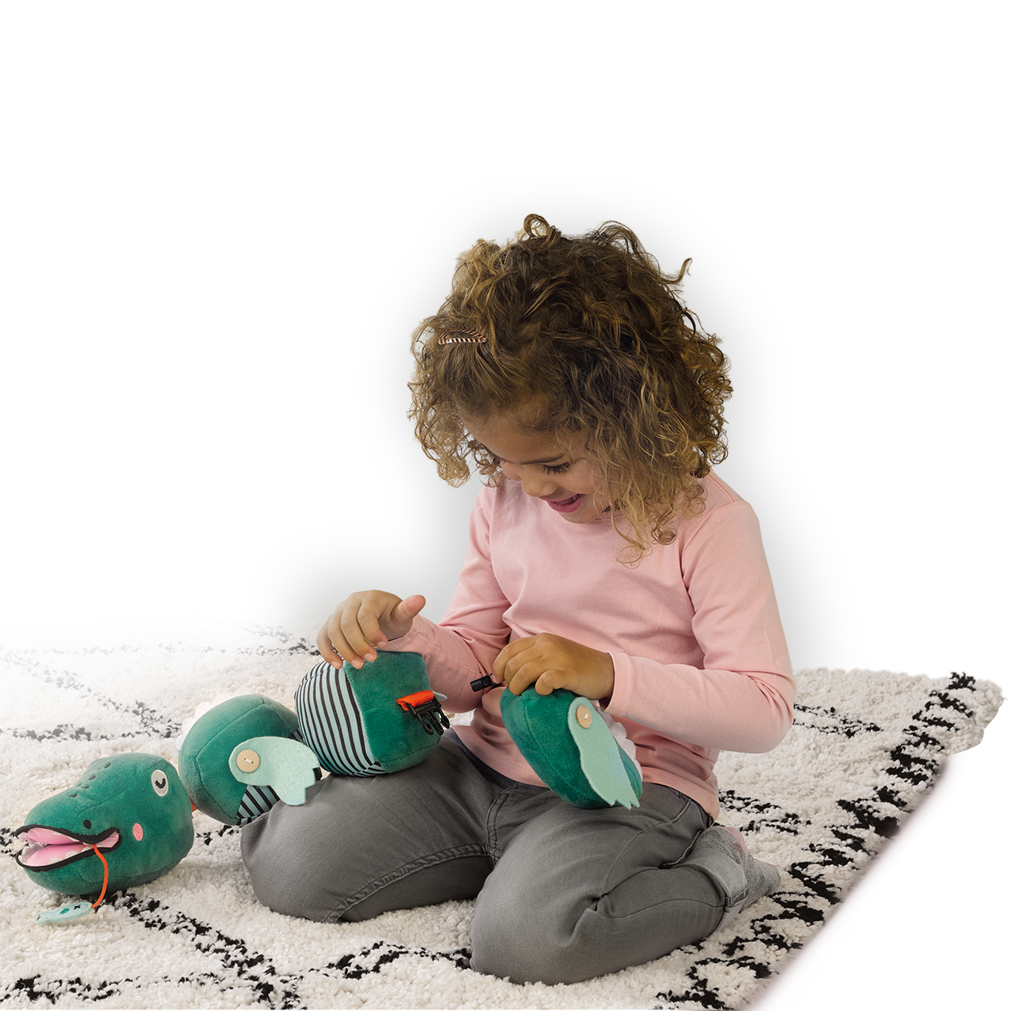 Una bambina gioca con giocattoli di coccodrillo di peluche su un tappeto.