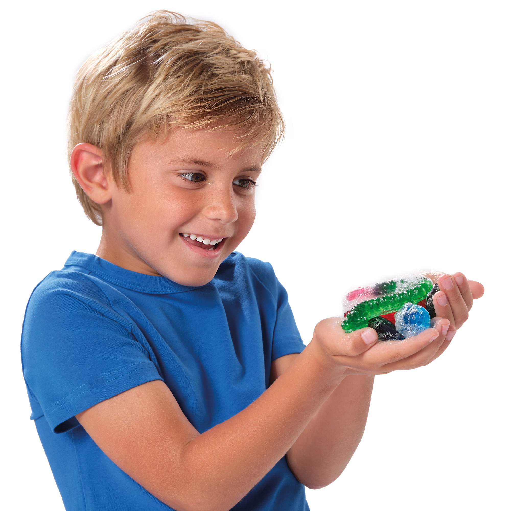 Uśmiechnięty chłopiec trzyma w otwartych dłoniach kolorowe, półprzezroczyste kulki i koraliki.