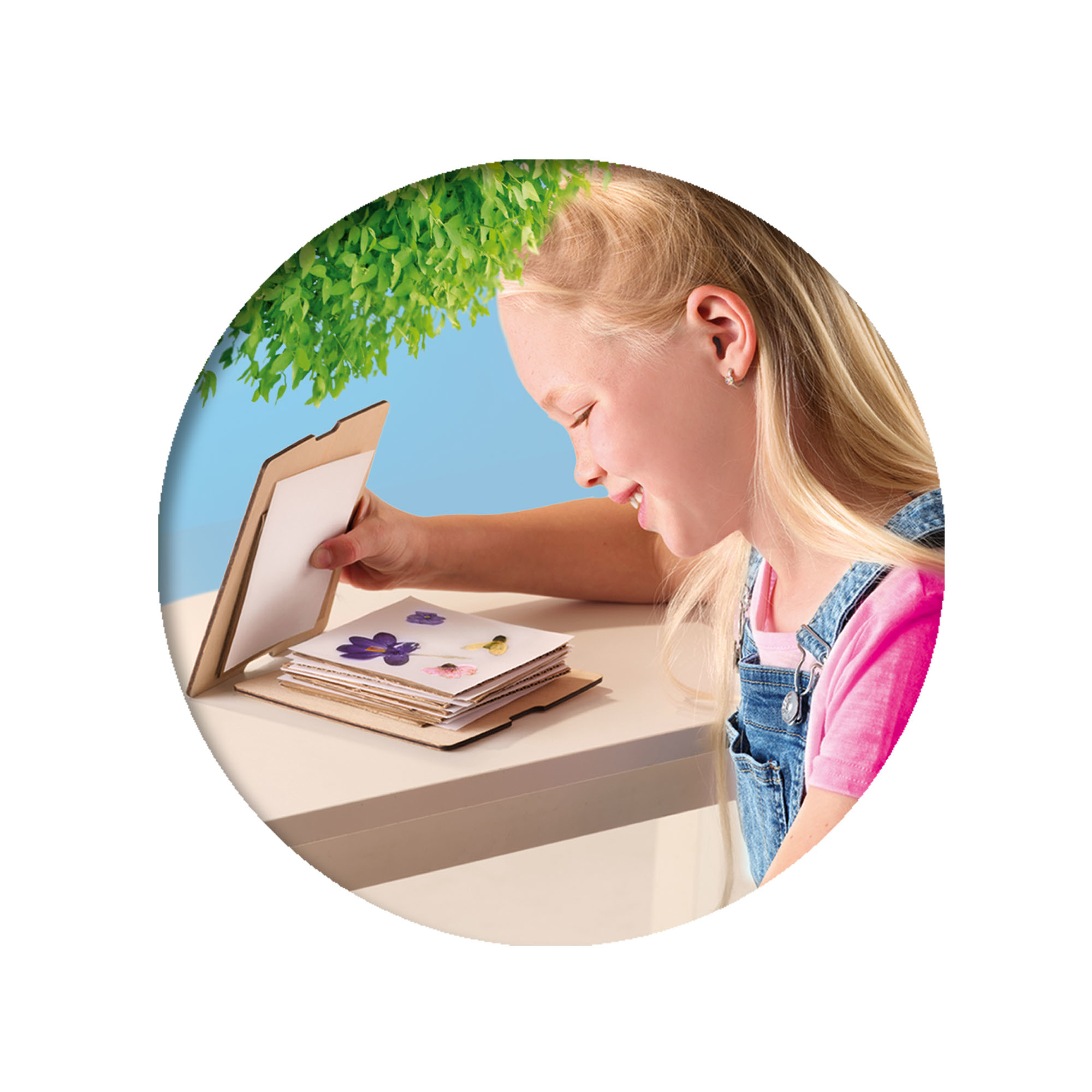 Dziewczyna ogląda album ze zdjęciami. Zdjęcie jest zbliżeniem. W tle jest drzewo.