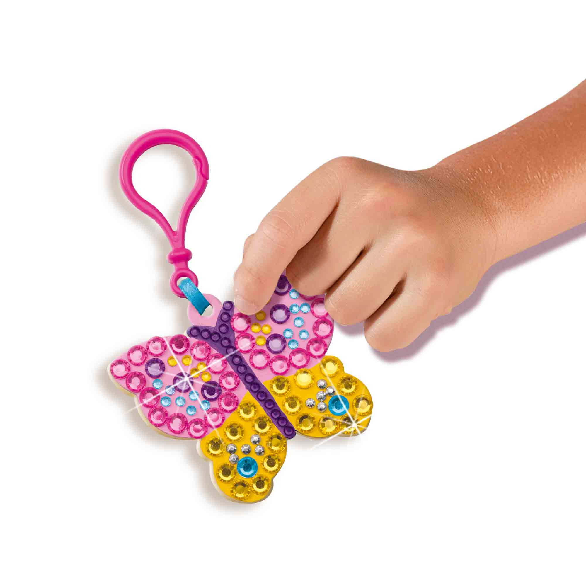 Dłoń dziecka trzymająca zawieszkę motyla, różową i żółtą, z koralikami. Różowa pętla u góry.