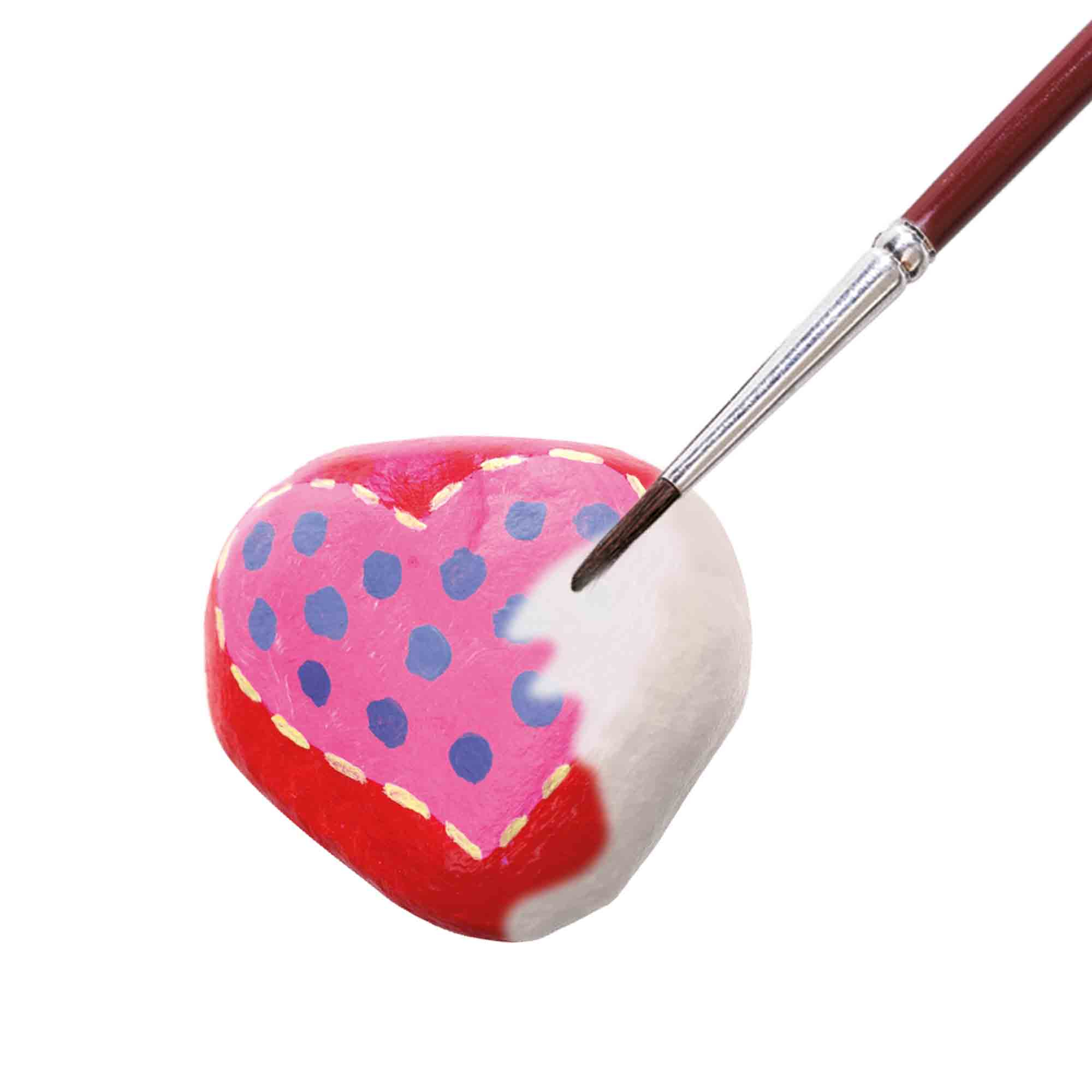 Pędzel maluje różowe serce z niebieskimi kropkami na białym tle.