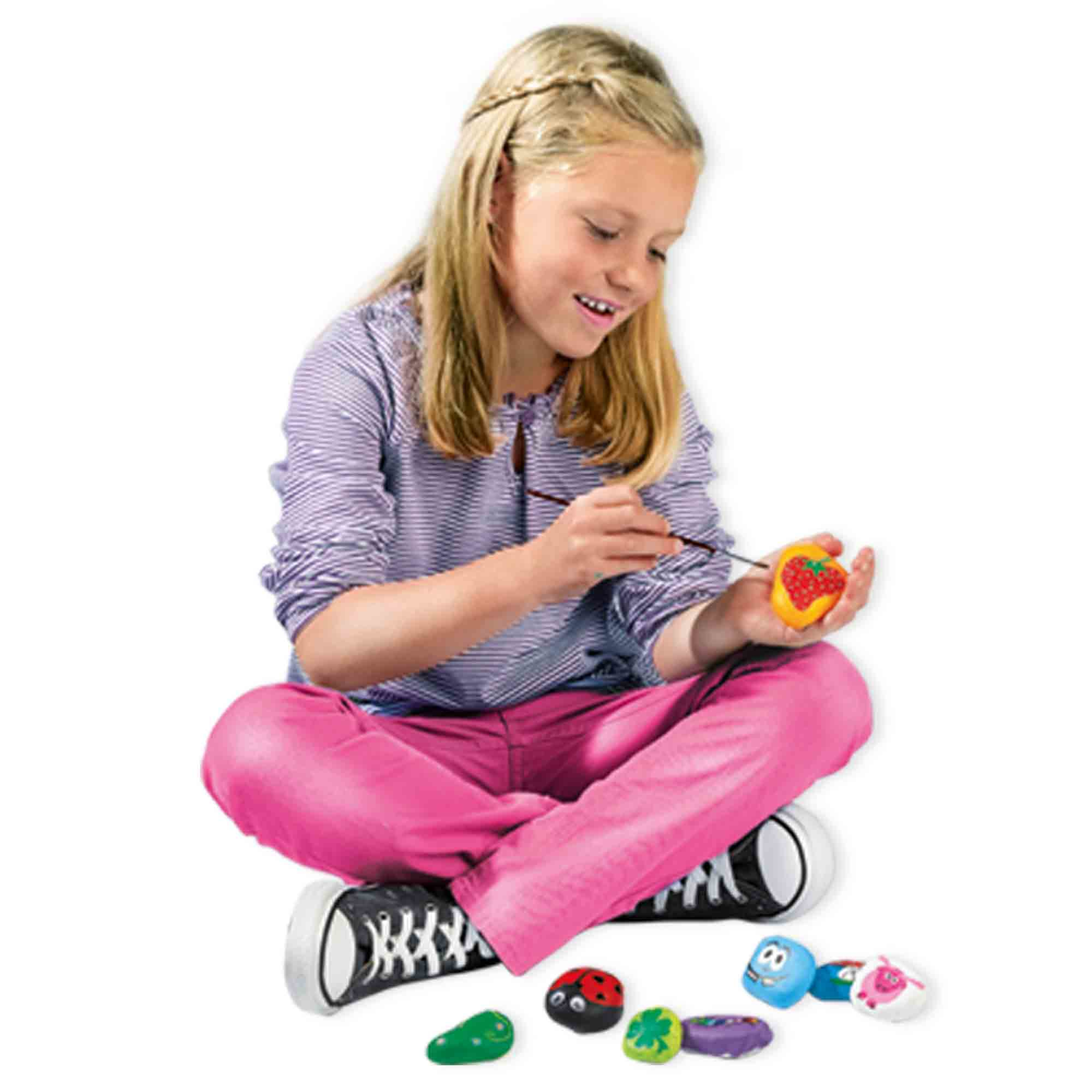 Dziewczynka maluje kamień w kształcie truskawki. Wokół niej inne pomalowane kamienie.