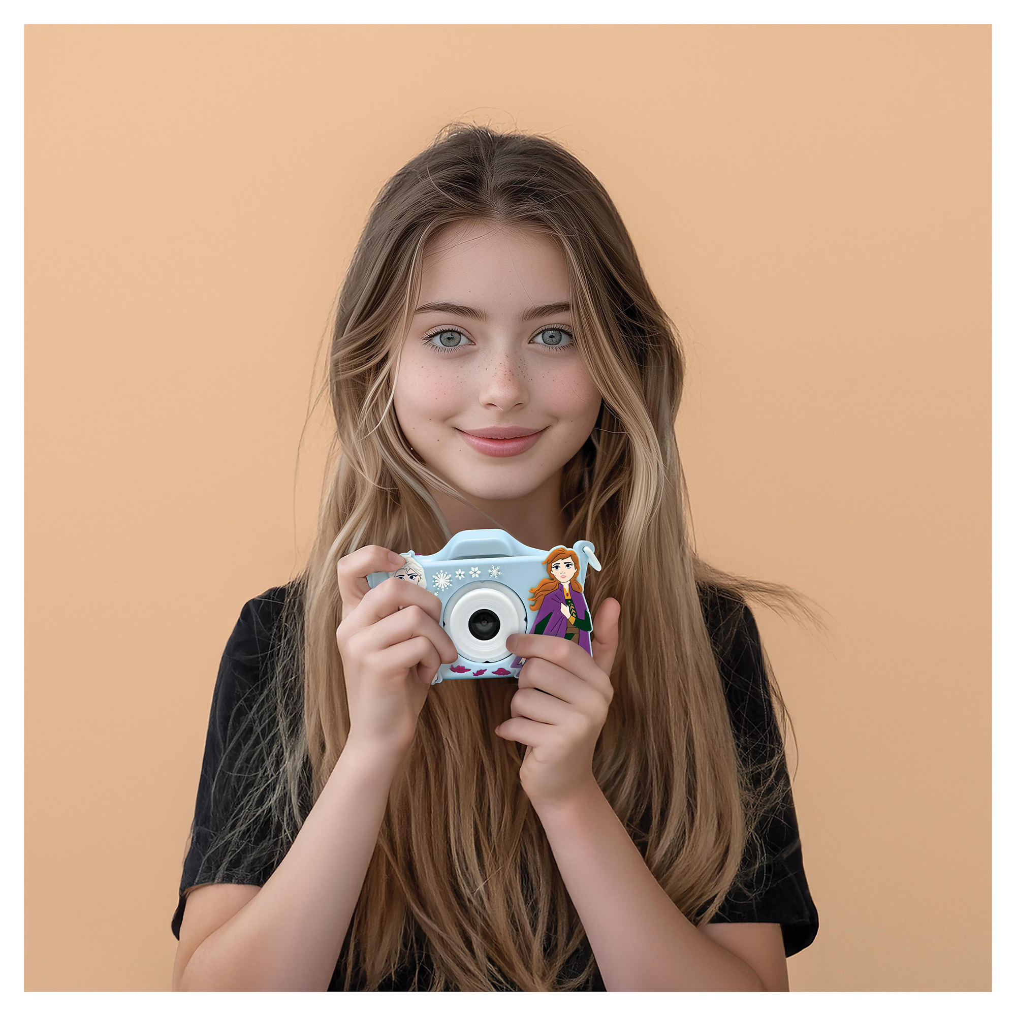 Una ragazza tiene in mano una fotocamera Frozen. Ha i capelli lunghi e un viso sorridente.