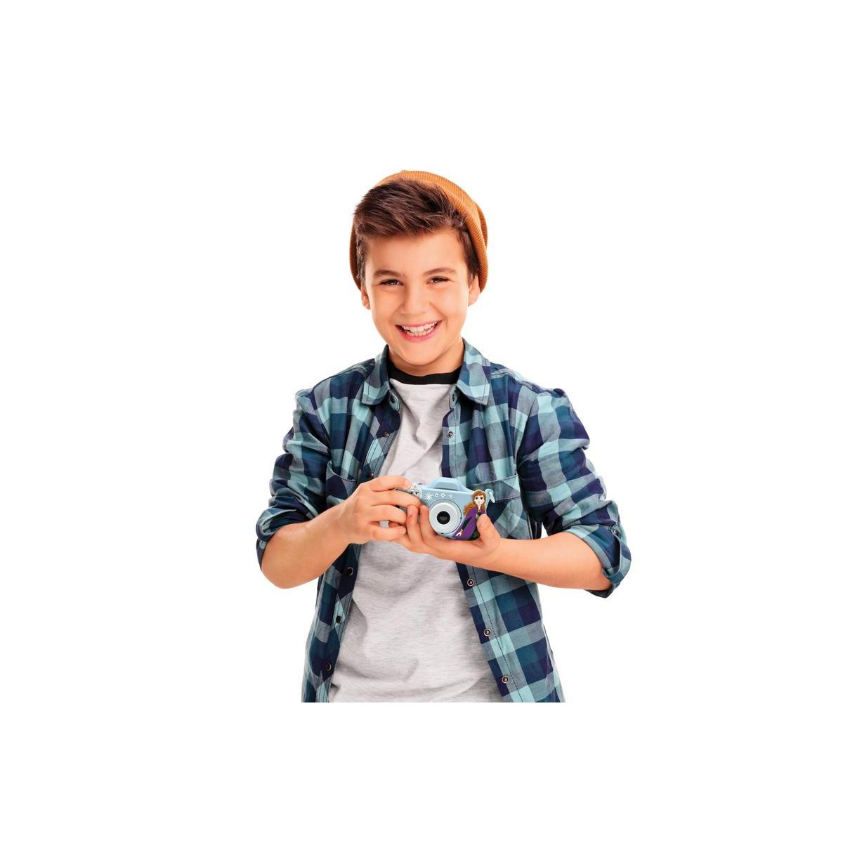 Un ragazzino sorride mentre tiene in mano una fotocamera blu a tema Frozen.