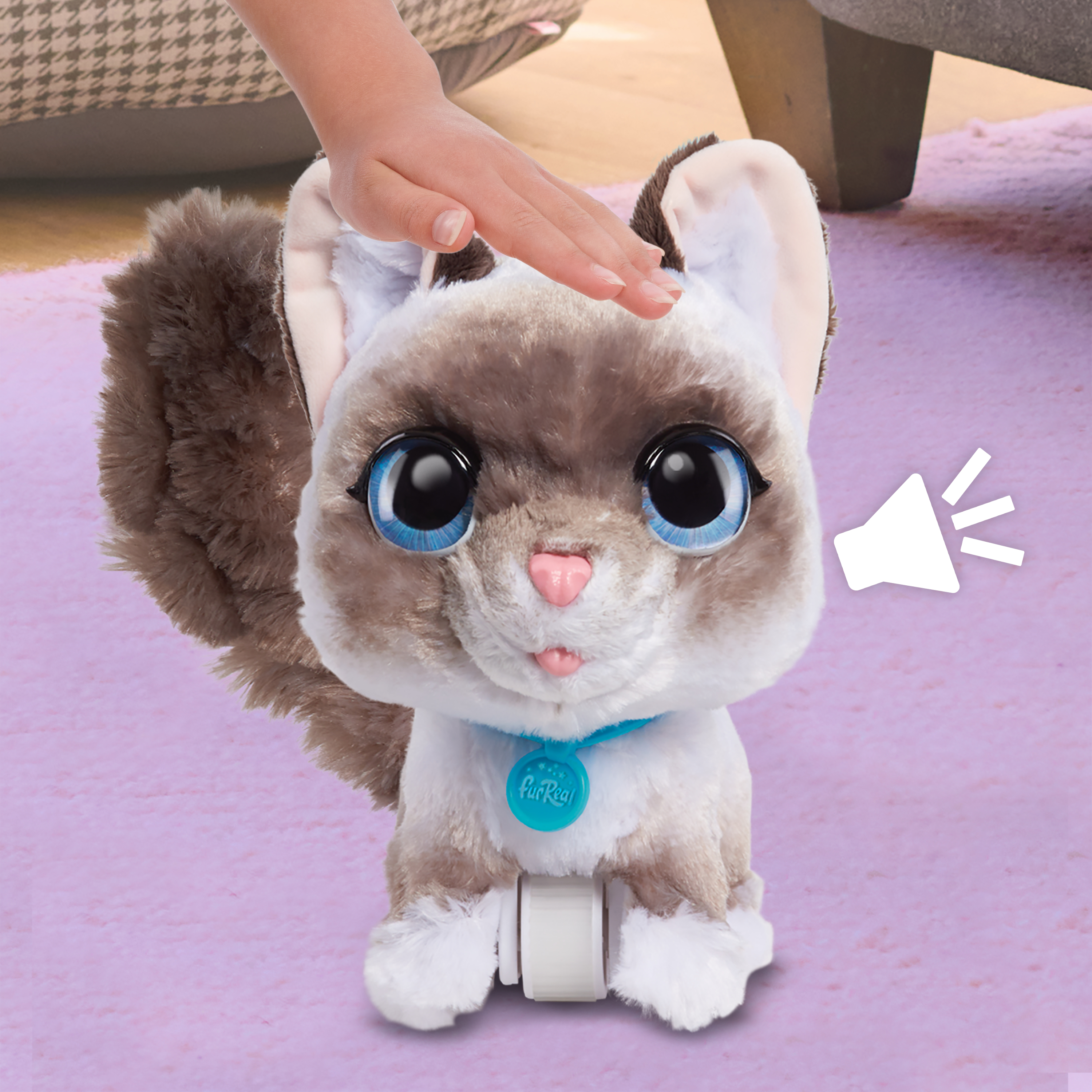 Un gato de juguete con grandes ojos azules y un collar azul. Una mano acaricia su cabeza, símbolo de efecto de sonido.