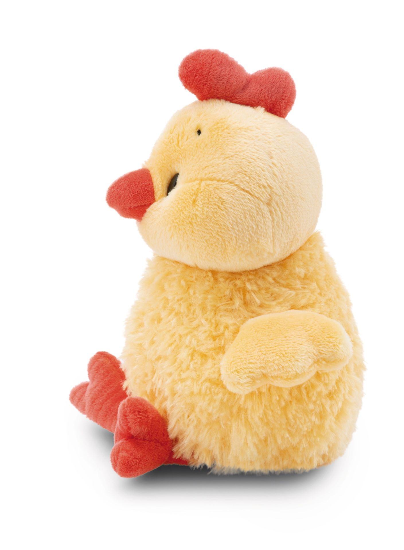 Żółta pluszowa zabawka kurczaka z czerwonym grzebieniem, dziobem i stopami, siedząca na białej powierzchni, widok z boku.