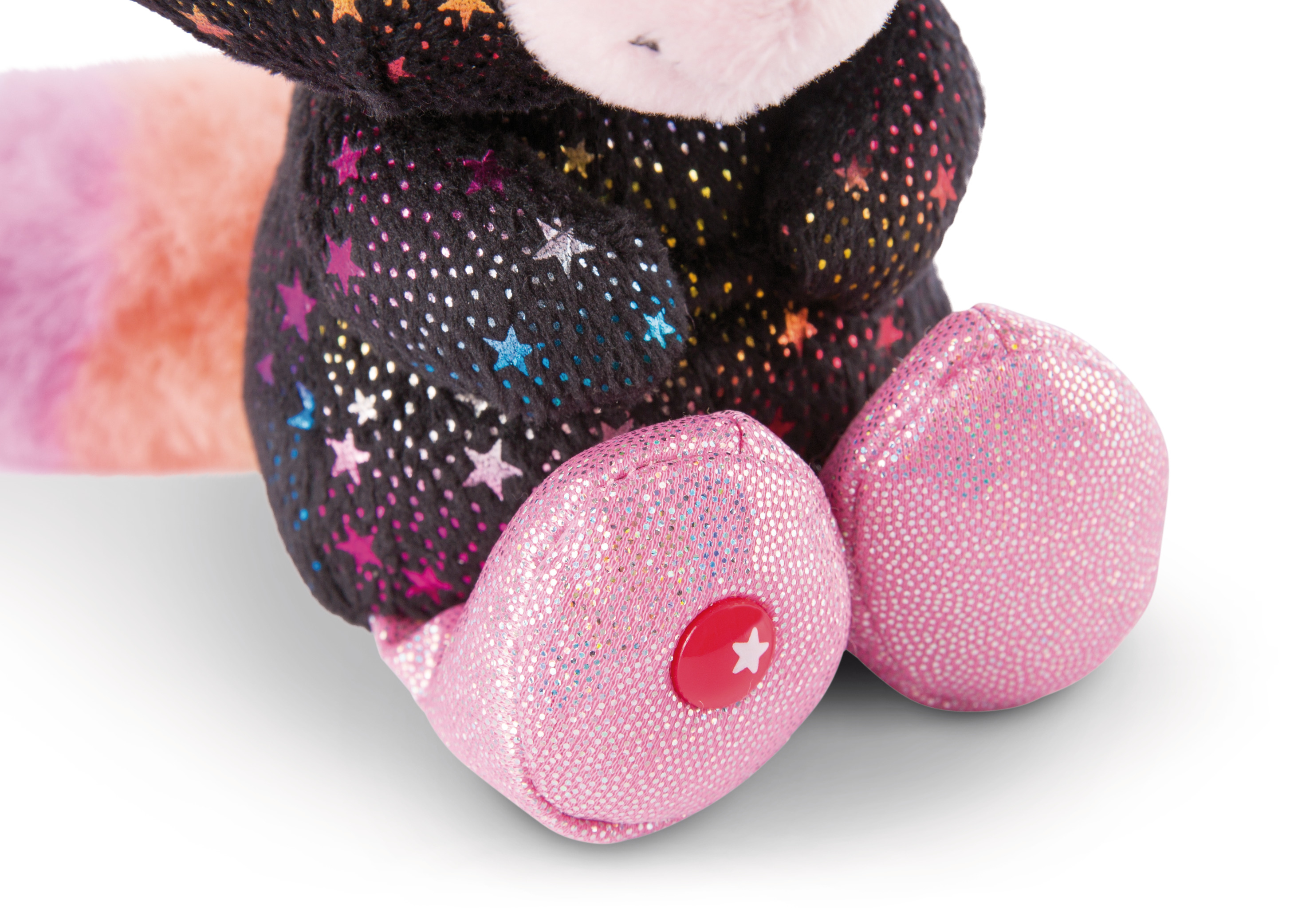 Zbliżenie czarnej zabawki kota, widok z boku. Różowe stopy, gwiazda na stopie, na białej powierzchni.