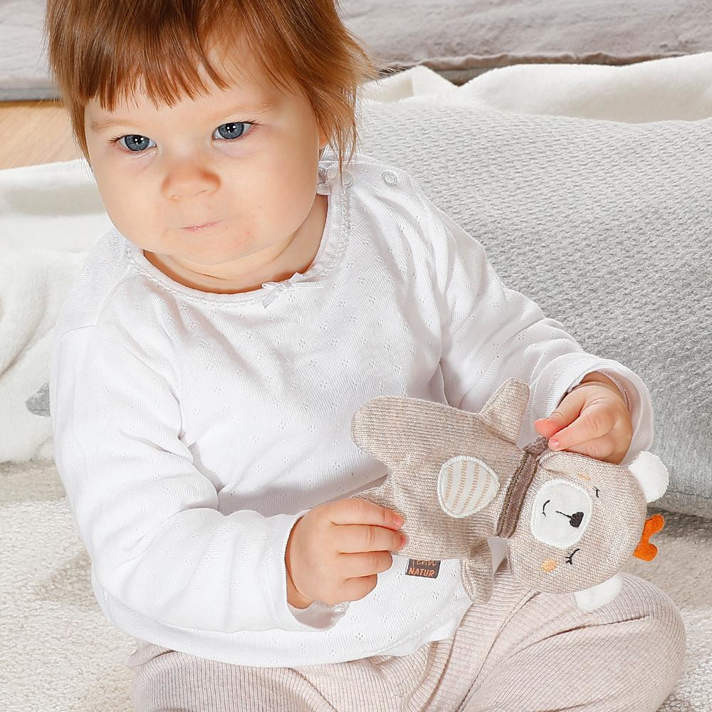 Dziecko trzymające zabawkę misia. Dziecko ma na sobie białą koszulę i różowe spodnie.