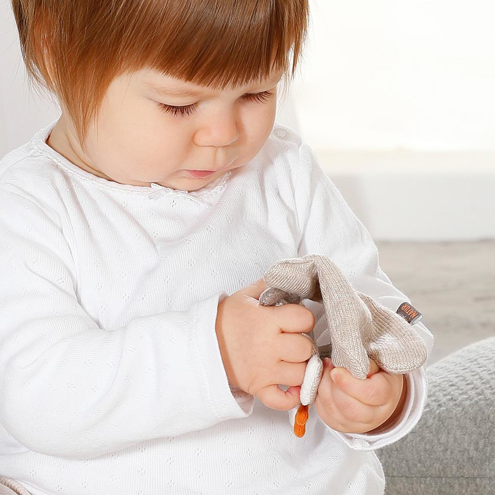 Dziecko trzymające beżową zabawkę królika. Ma na sobie białą koszulę.