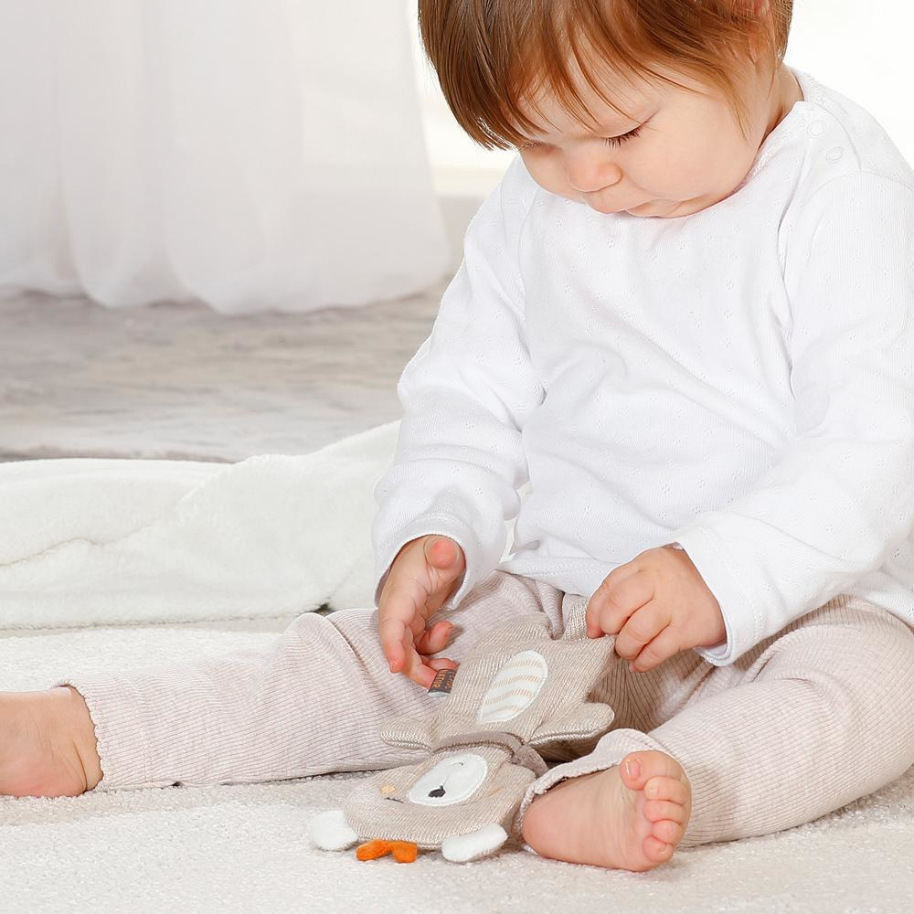 Dziecko bawi się zabawką. Dziecko ma na sobie białą koszulę i spodnie.