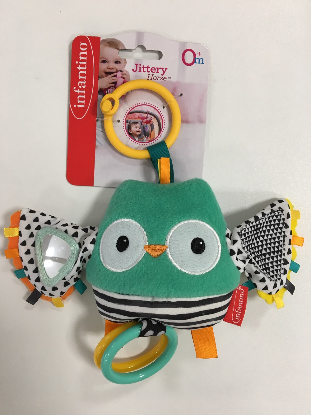 Zabawka w kształcie sowy z różnymi kolorami i wzorami, z białym tłem i etykietą.