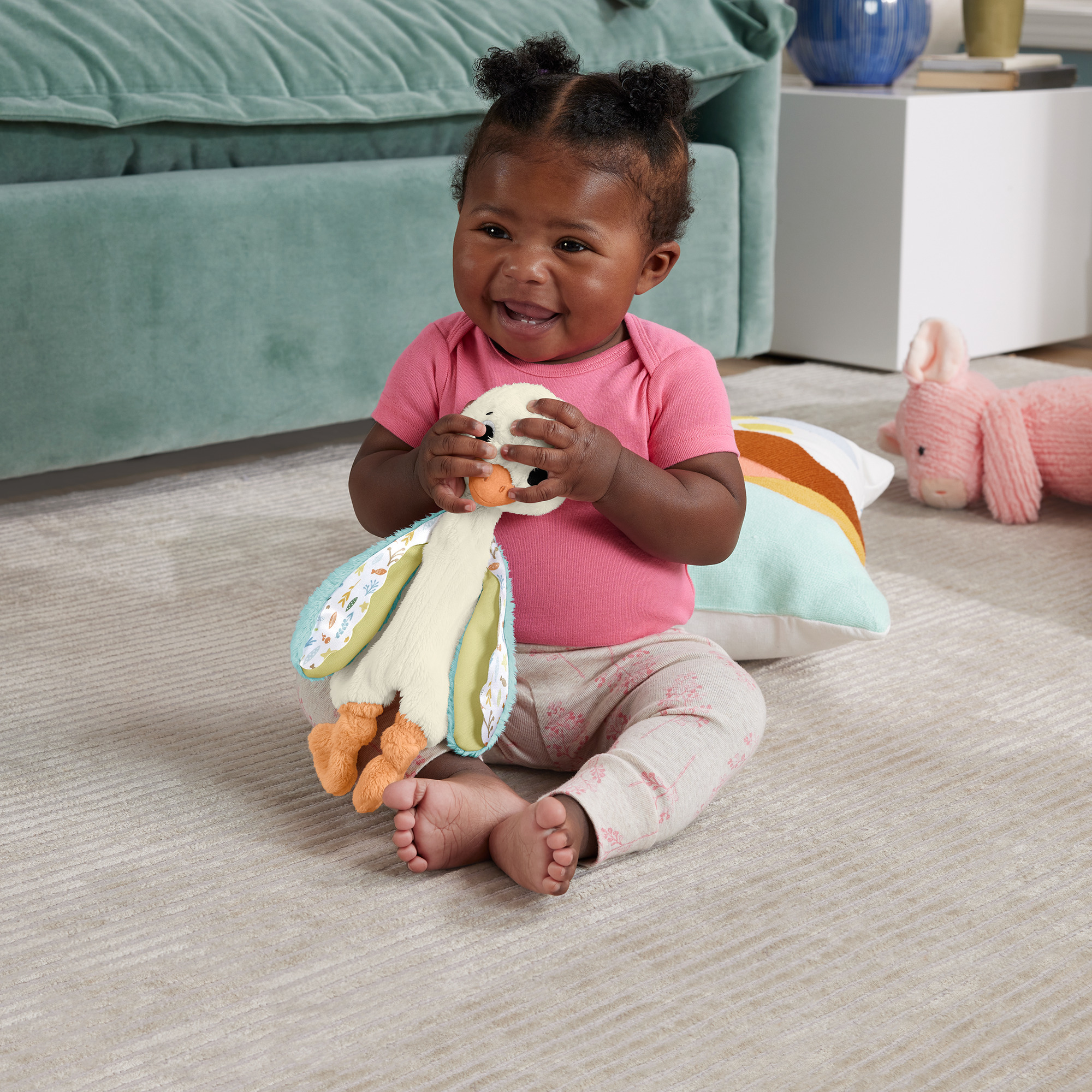 Dziewczynka trzyma pluszową kaczkę, uśmiechając się na dywanie.