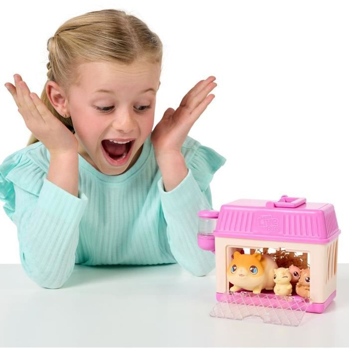 Dziewczyna jest podekscytowana, patrząc na zabawkę Little Live Pets z trzema figurkami chomików.