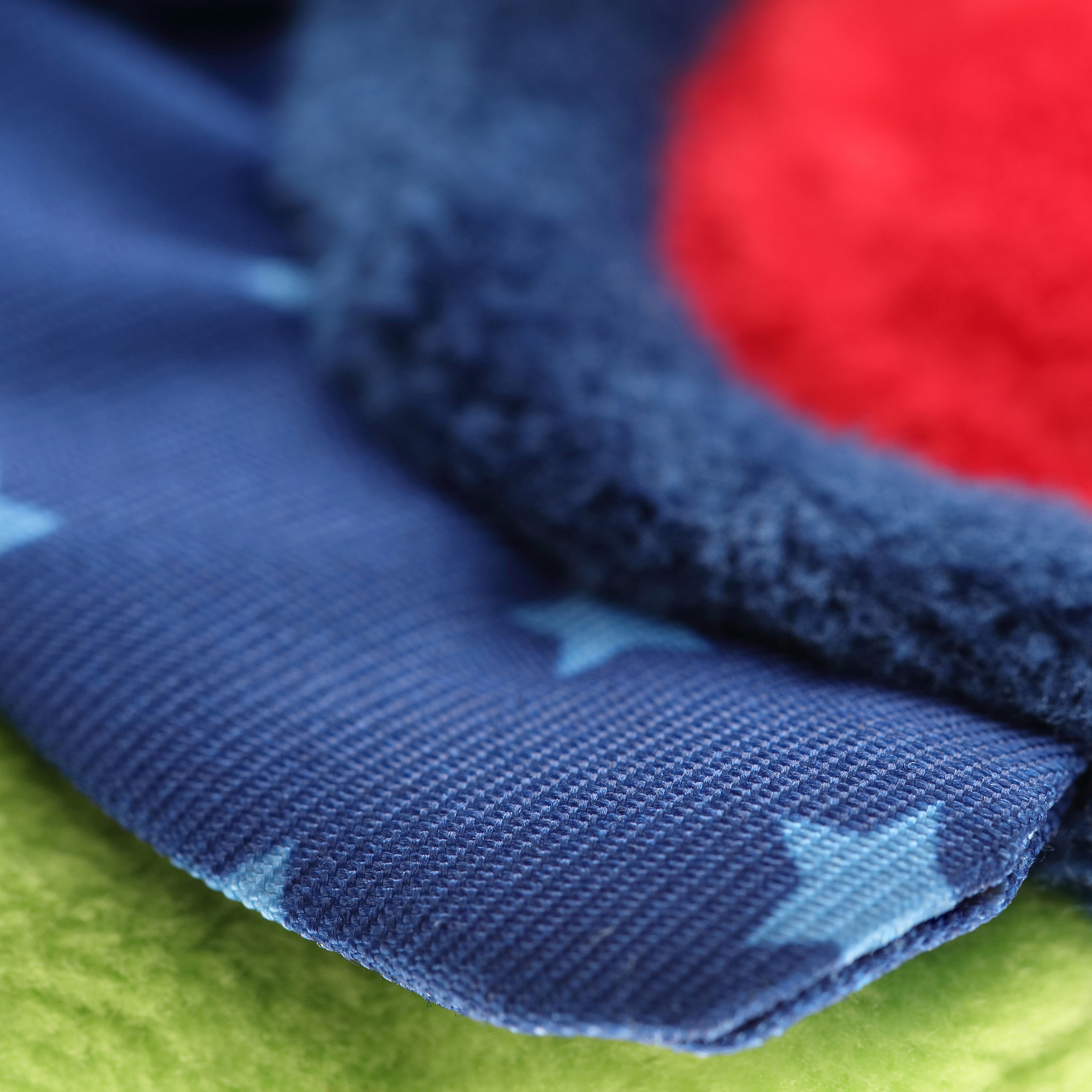 Zbliżenie tkaniny z niebieskimi gwiazdami na granatowych, czerwonych i zielonych teksturach.