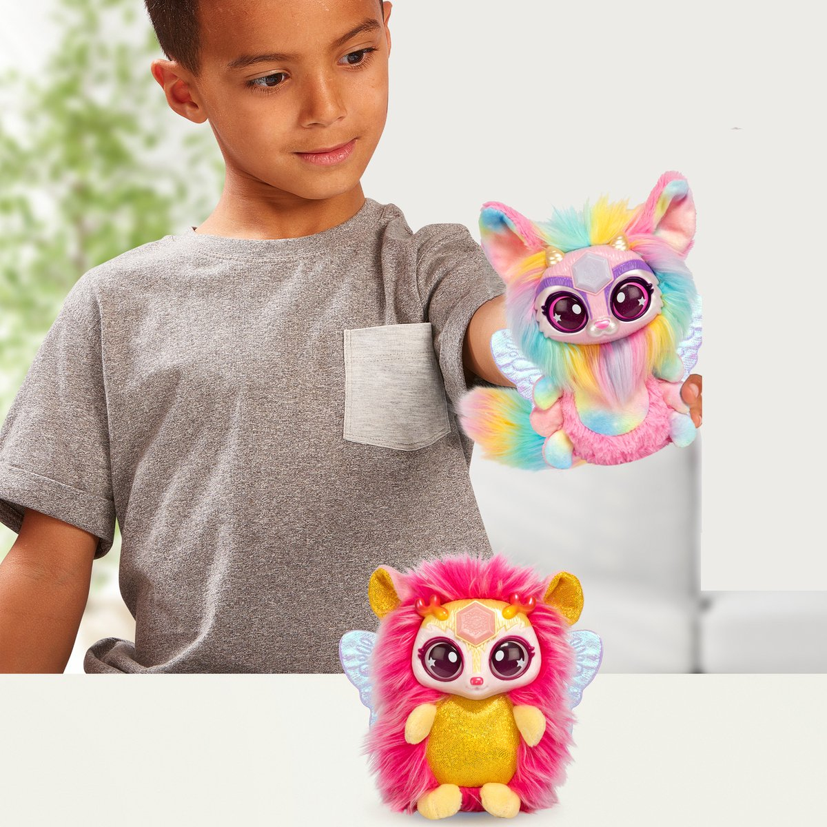 Dziecko trzyma dwa kolorowe pluszowe stworzenia. Tło to jasna powierzchnia i okno.