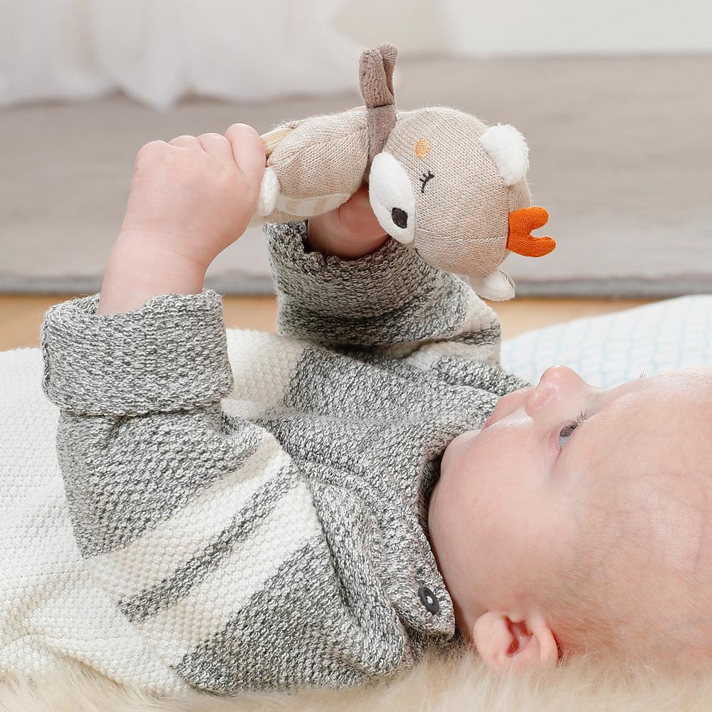 Bambino che guarda in alto tenendo in mano un giocattolo a forma di cervo. Il bambino indossa un maglione a righe grigio e bianco.