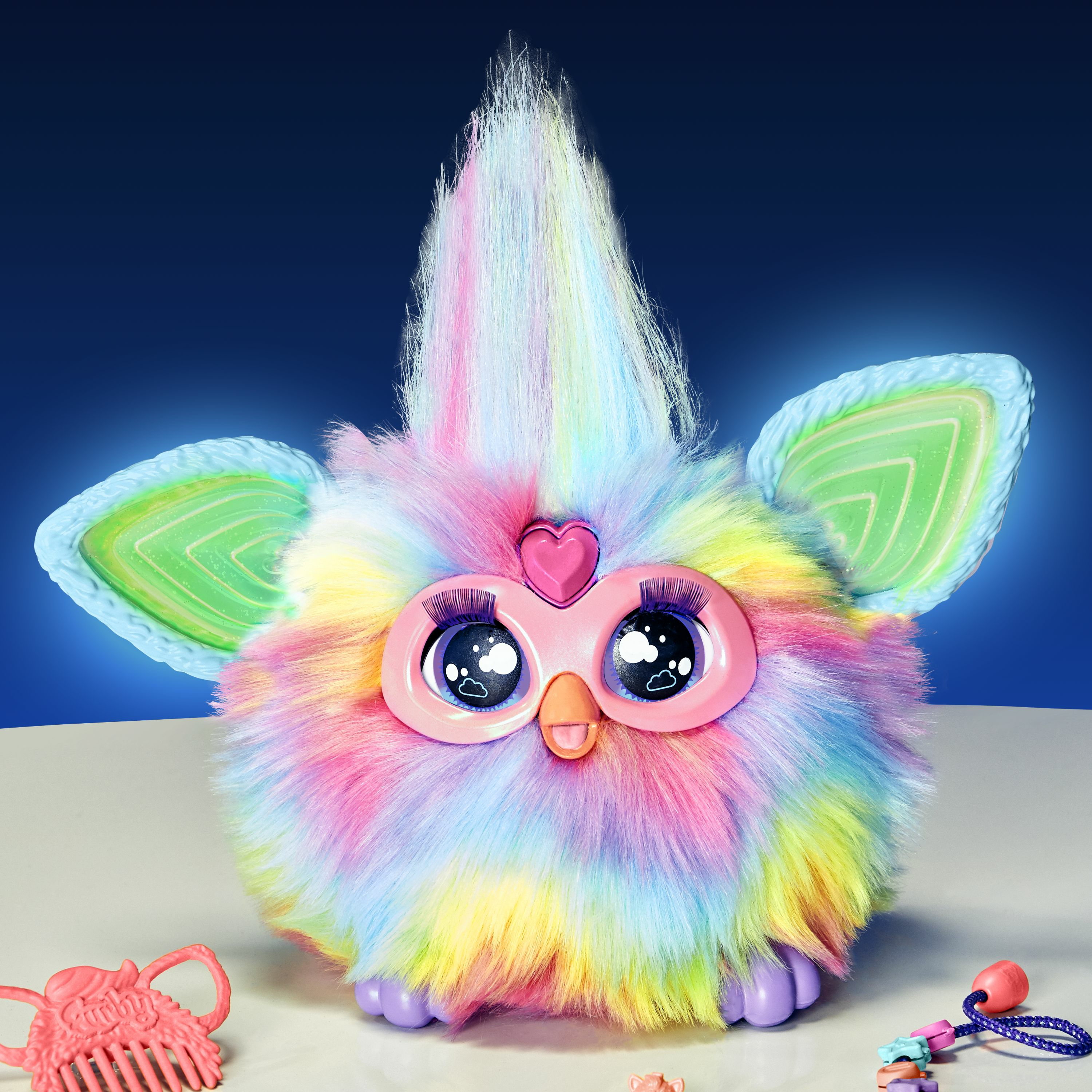 Kolorowa zabawka Furby z akcesoriami. Ma serce, dwoje oczu i puszysty korpus.