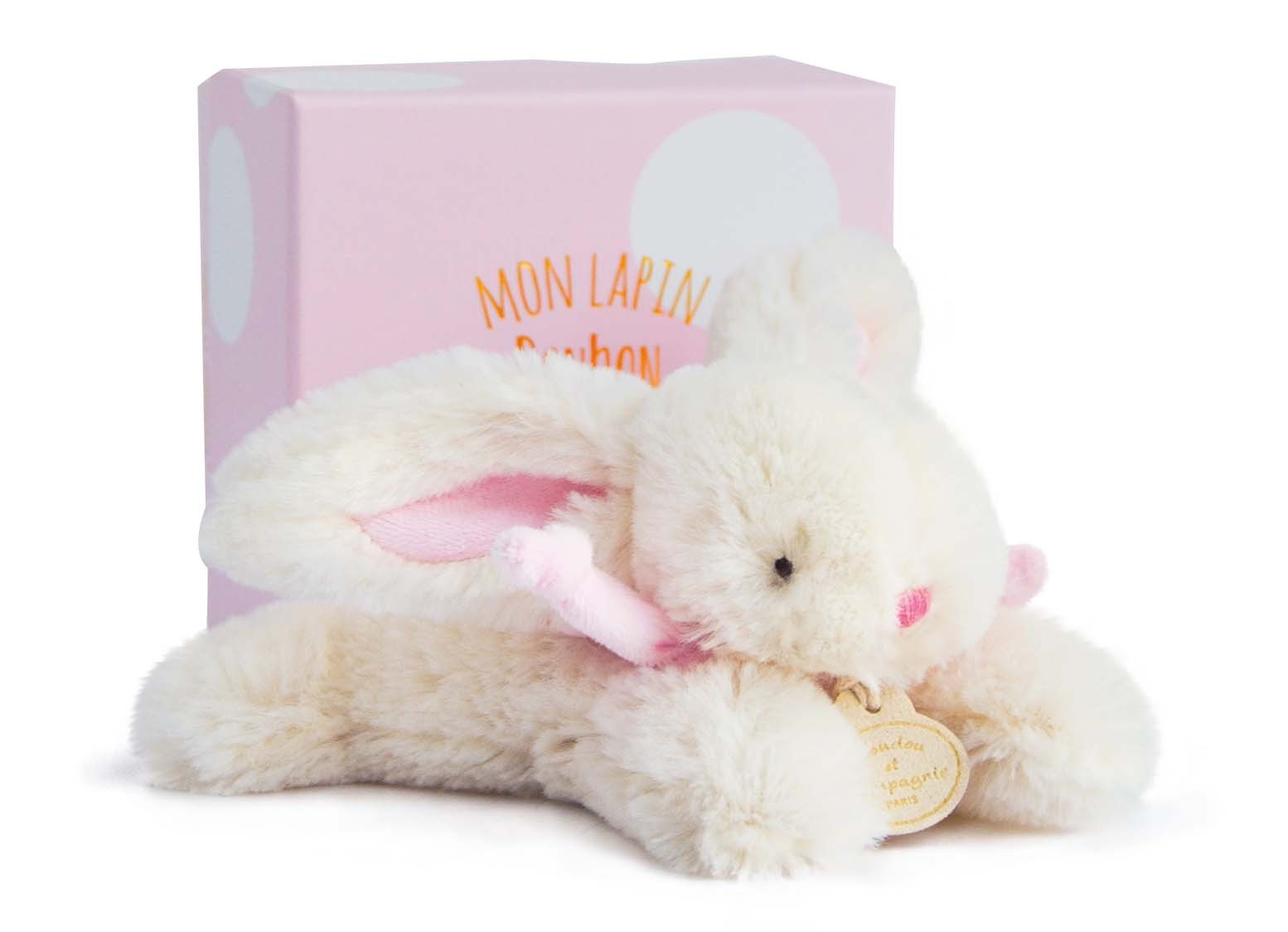 Un giocattolo a forma di coniglio di peluche bianco con orecchie e dettagli rosa. È accanto a una scatola regalo rosa.