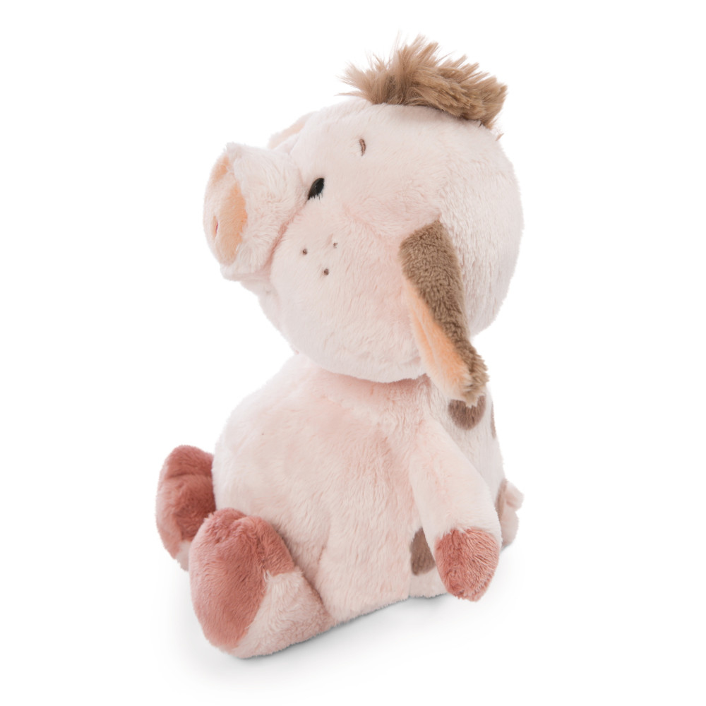 Un giocattolo a forma di maiale di peluche rosa con macchie marroni. È seduto e guarda di lato.