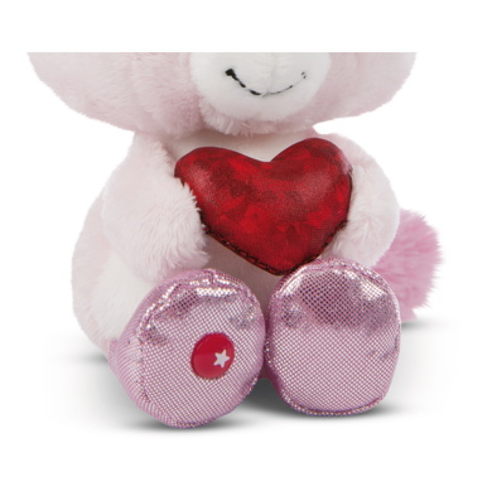 Różowy pluszowy jednorożec trzymający czerwone serce. Ma różowe, błyszczące buty i gwiazdkę na jednej stopie.