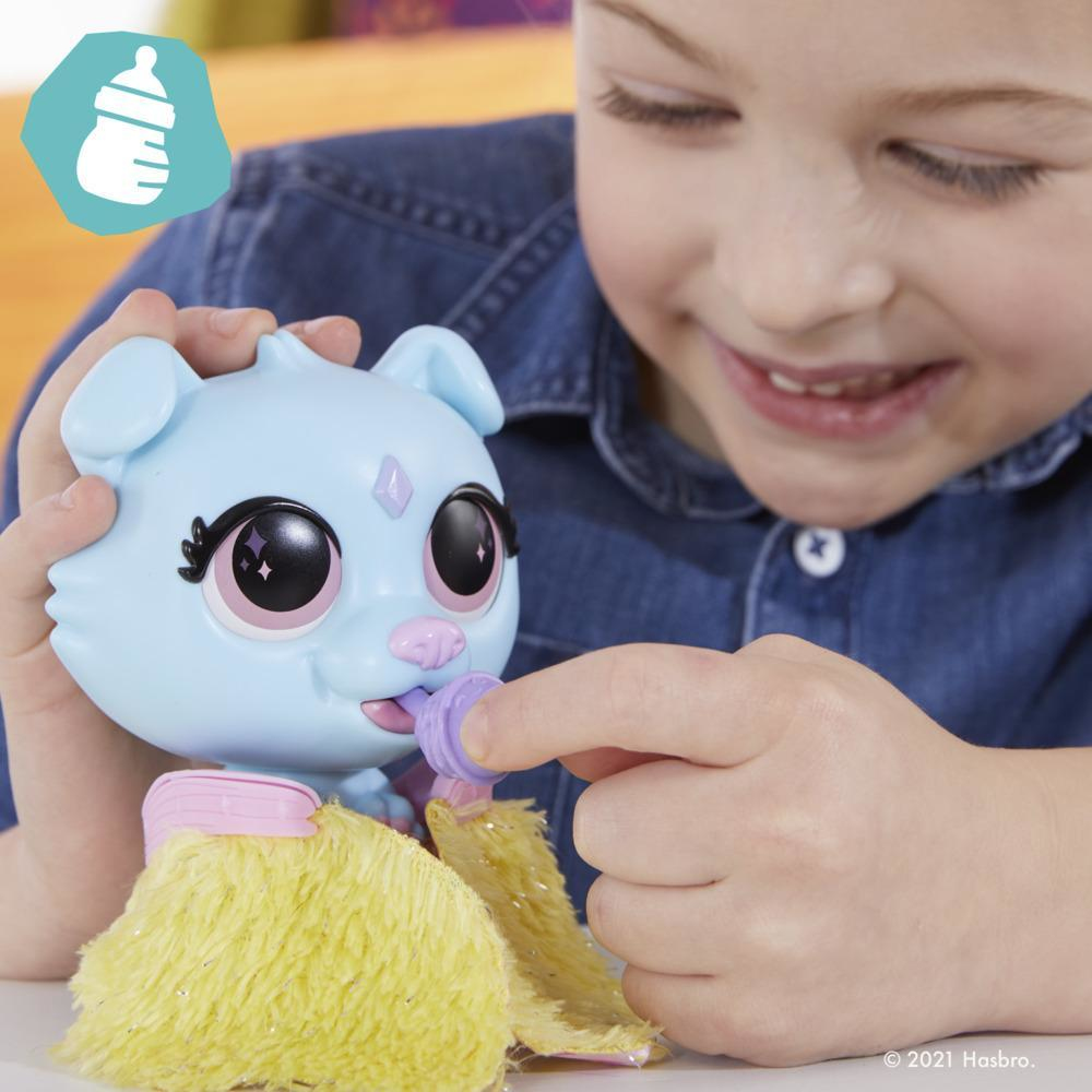 Un enfant nourrit un jouet de chiot bleu avec un biberon. L'enfant sourit.