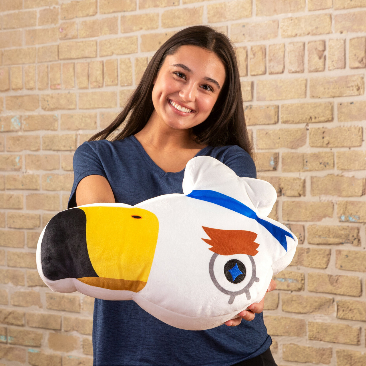 Kobieta trzyma białego pluszowego ptaka z żółtym dziobem i niebieską wstążką.