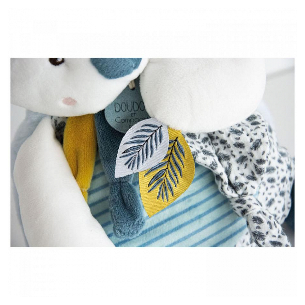 Un peluche con corpo blu e bianco, una foglia gialla e blu e uno sfondo blu.