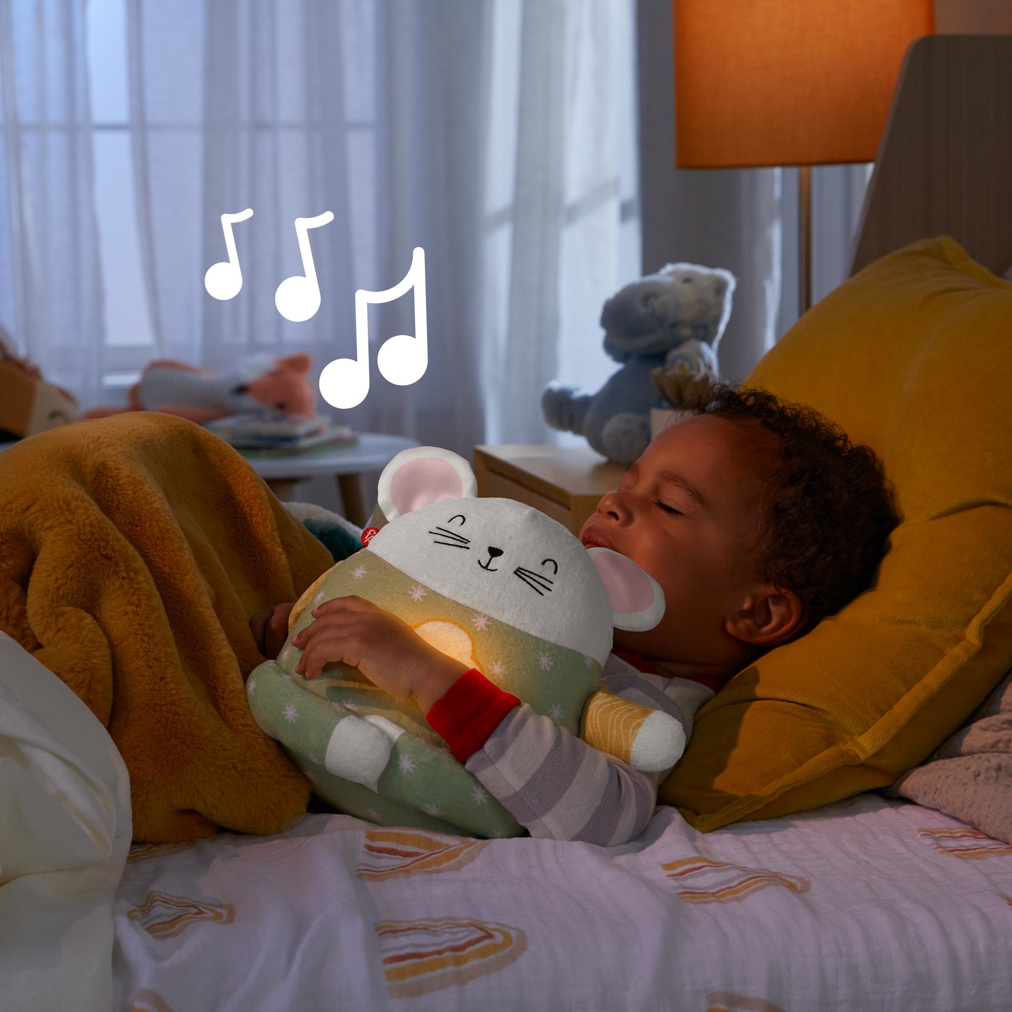 Dziecko śpi obok nocnej lampki w kształcie myszy, otoczone nutami. Pokój jest słabo oświetlony.