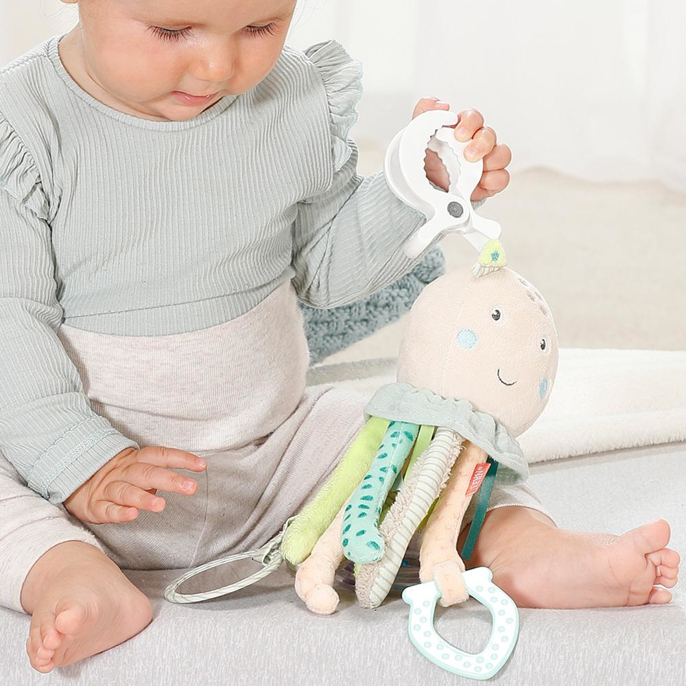 Niemowlę trzyma pluszową zabawkę ośmiornicę. Ośmiornica ma kolorowe macki i przyjazną twarz.
