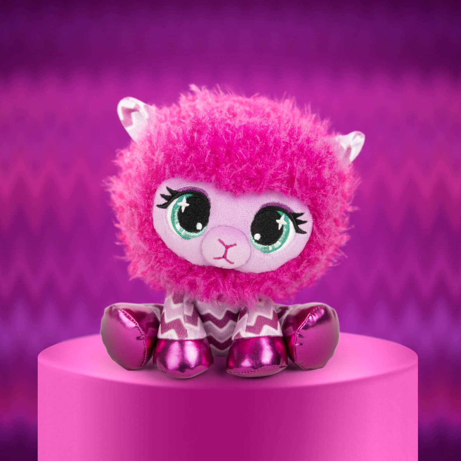 Różowa pluszowa zabawka lama na różowym cokole, z fioletowym tłem. Lama ma duże oczy.