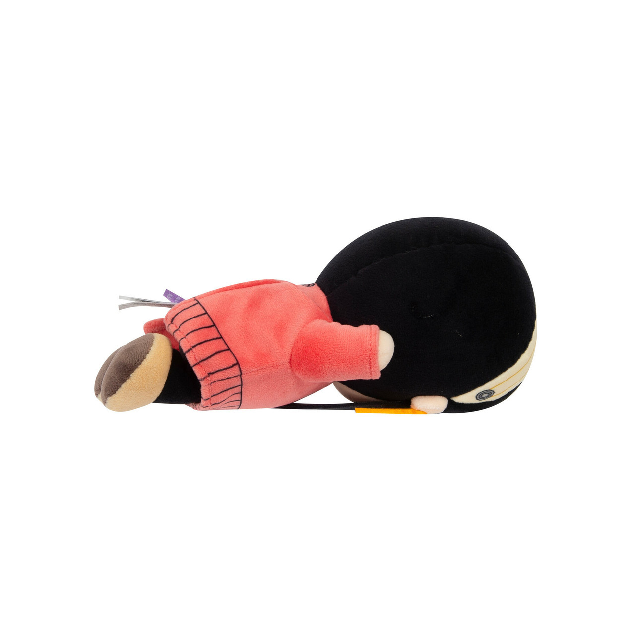 Una bambola di peluche sdraiata. Ha i capelli neri con un accessorio giallo e indossa un vestito rosso.