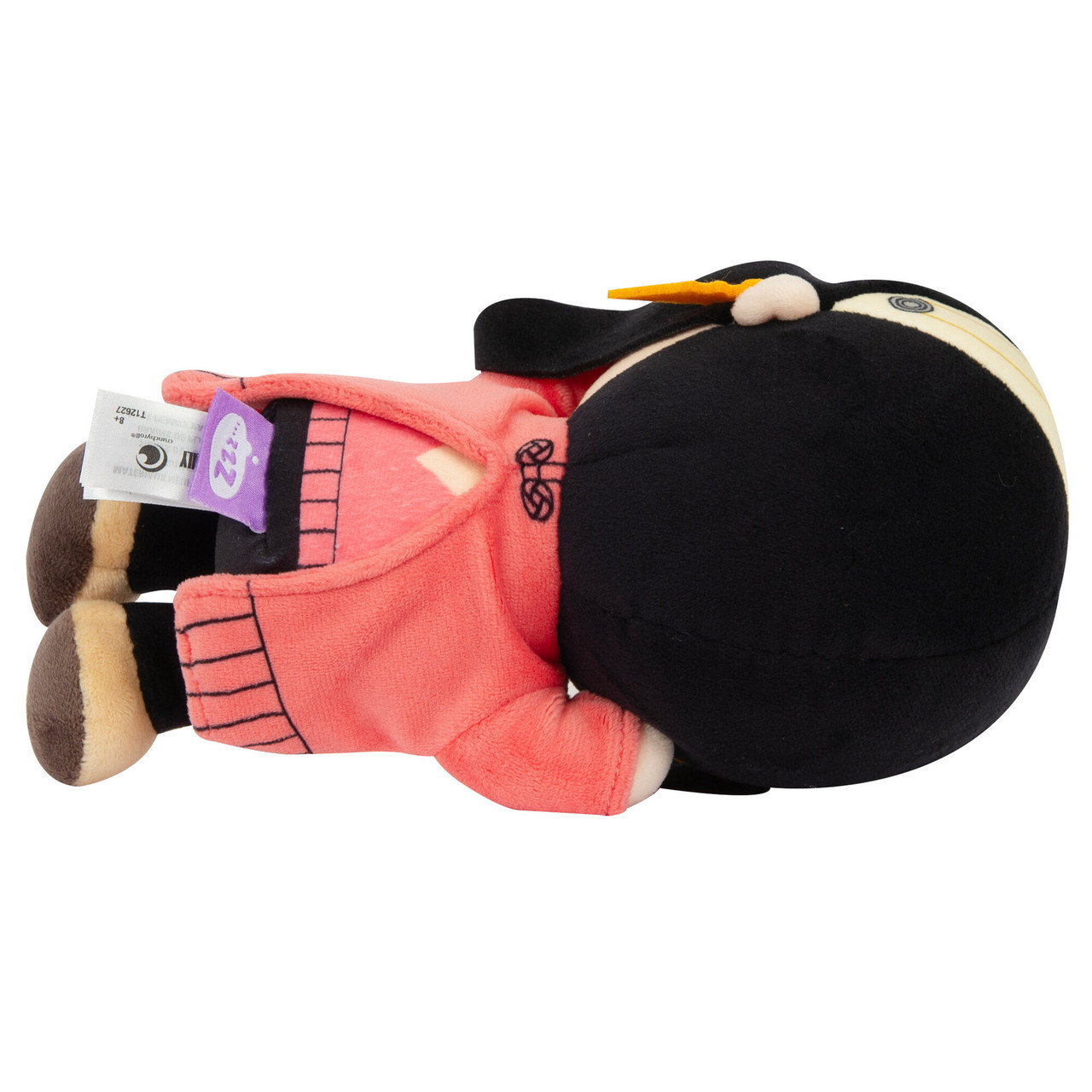 Una bambola di peluche in pigiama rosa con capelli neri, sdraiata su un fianco, sfondo bianco.