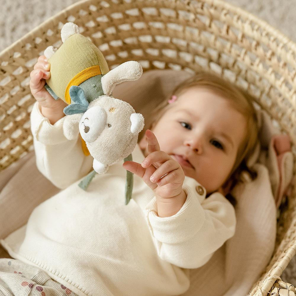 Un bambino tiene un coniglietto di peluche in un cesto di vimini. Il coniglietto è color crema.