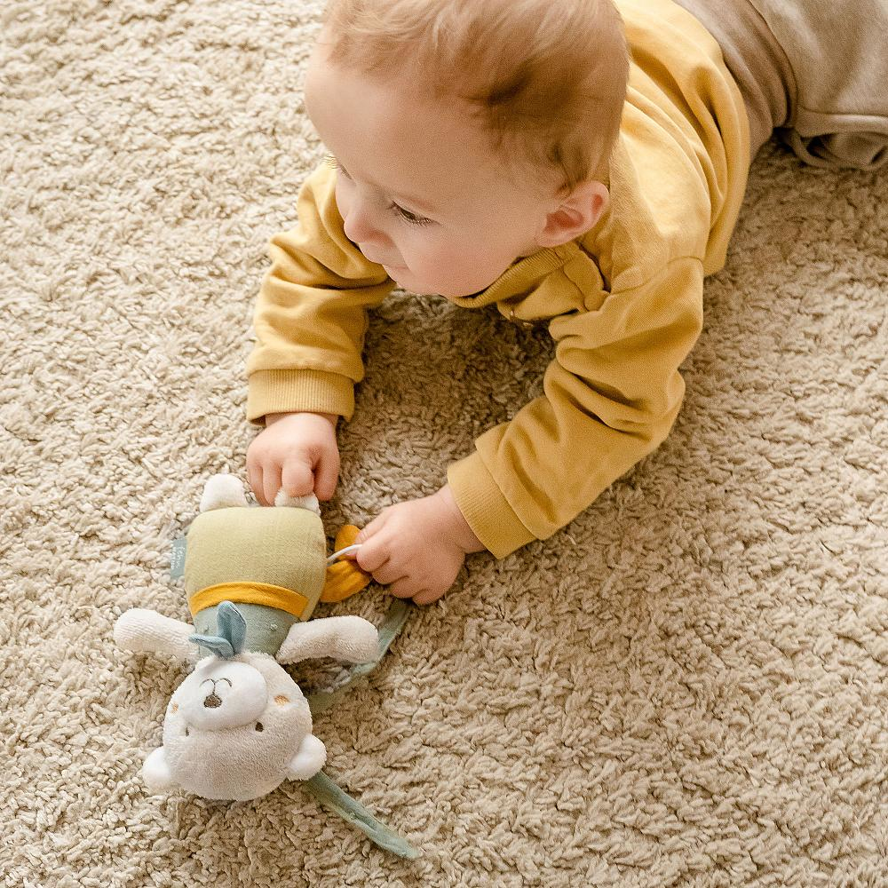 Bambino che gioca con un orsacchiotto musicale su un tappeto.