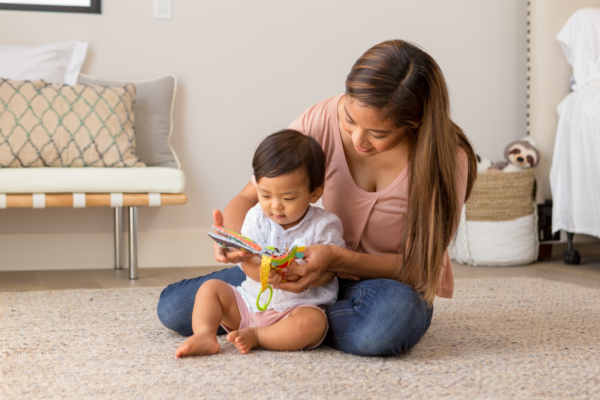 Madre e bambino giocano con un libro giocattolo colorato su un tappeto.