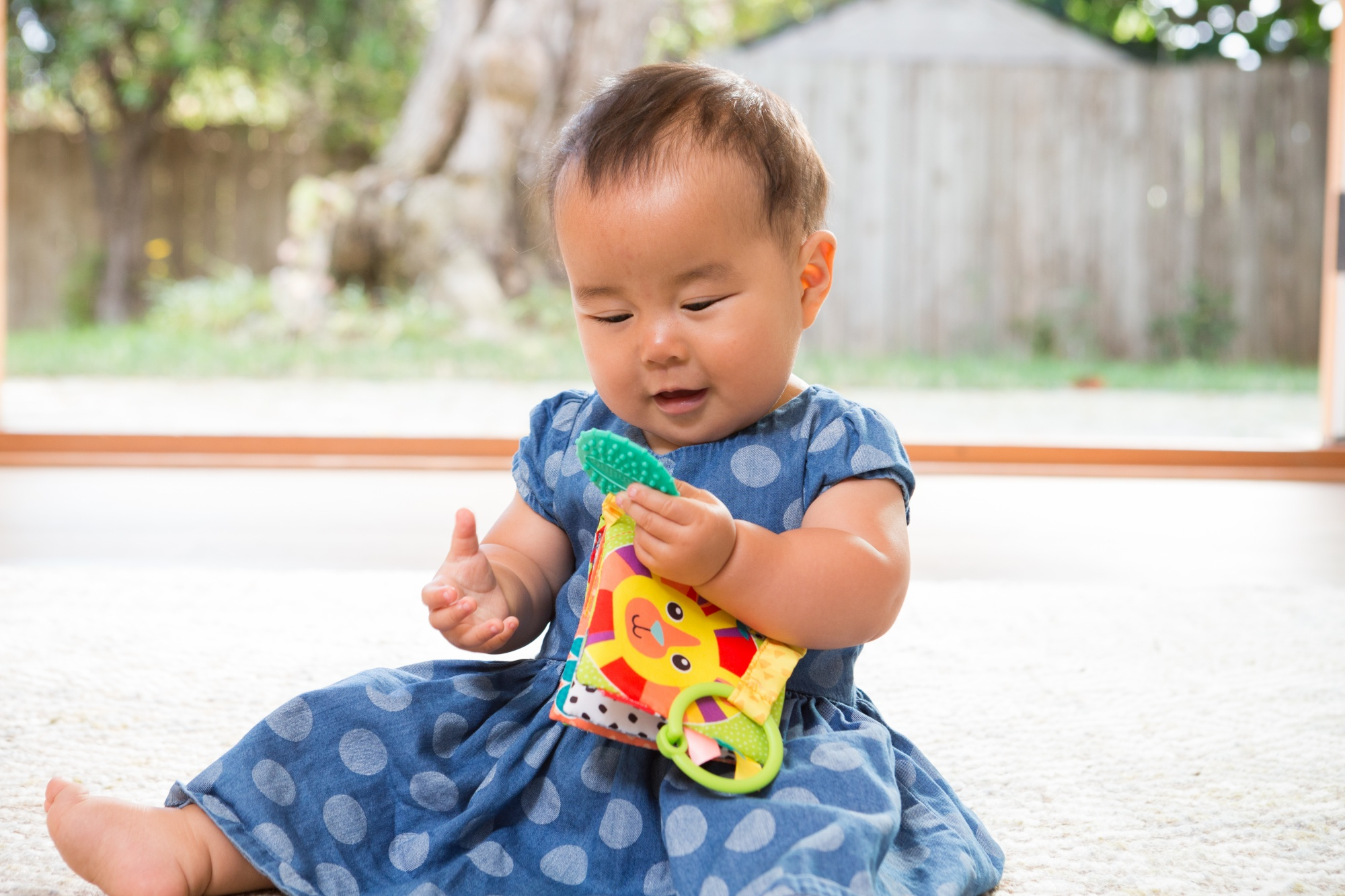 Bambino in vestito blu a pois che gioca con un libro giocattolo.