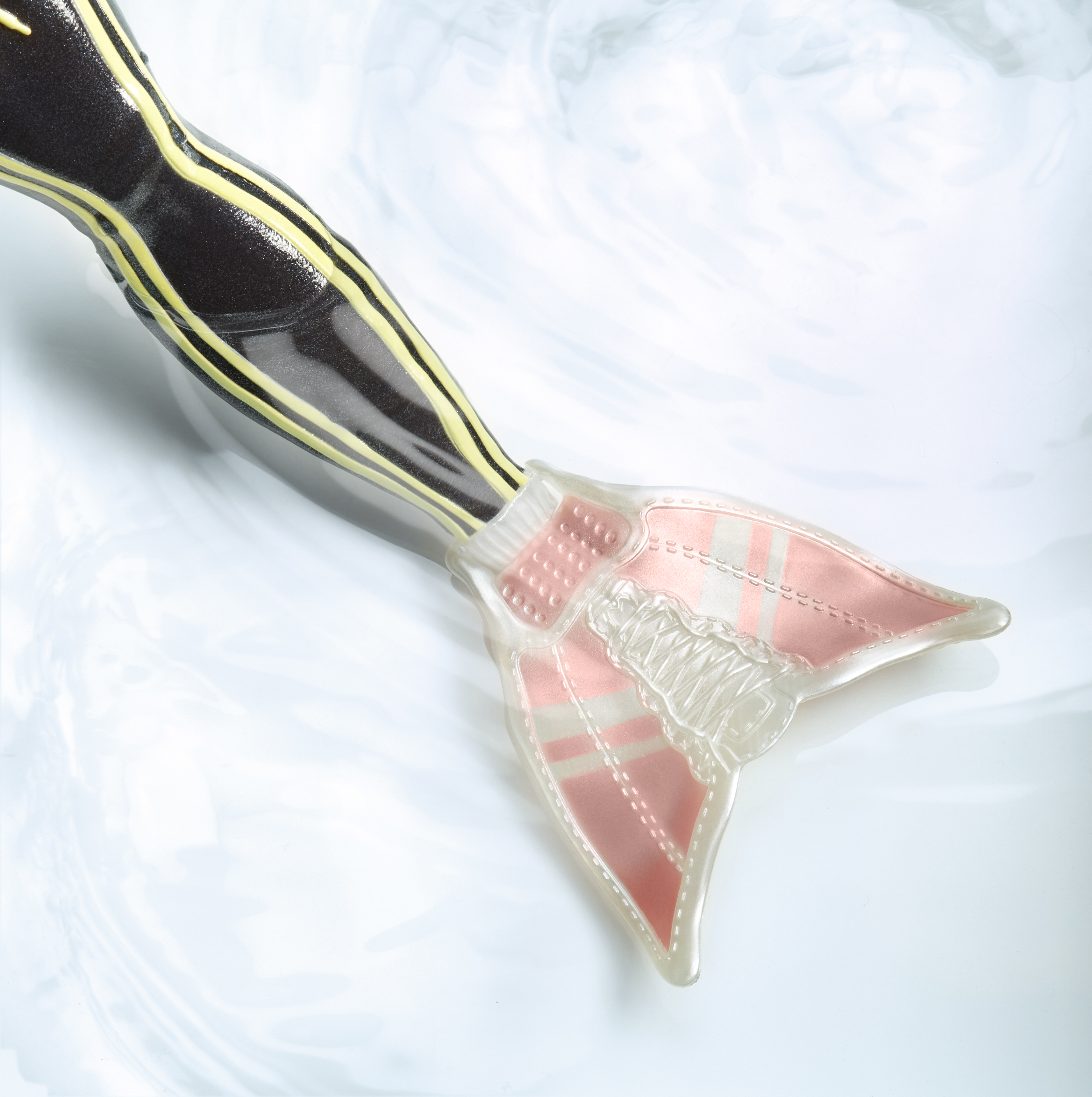 Primer plano de una cola de sirena. La cola es rosa y transparente, con rayas amarillas.
