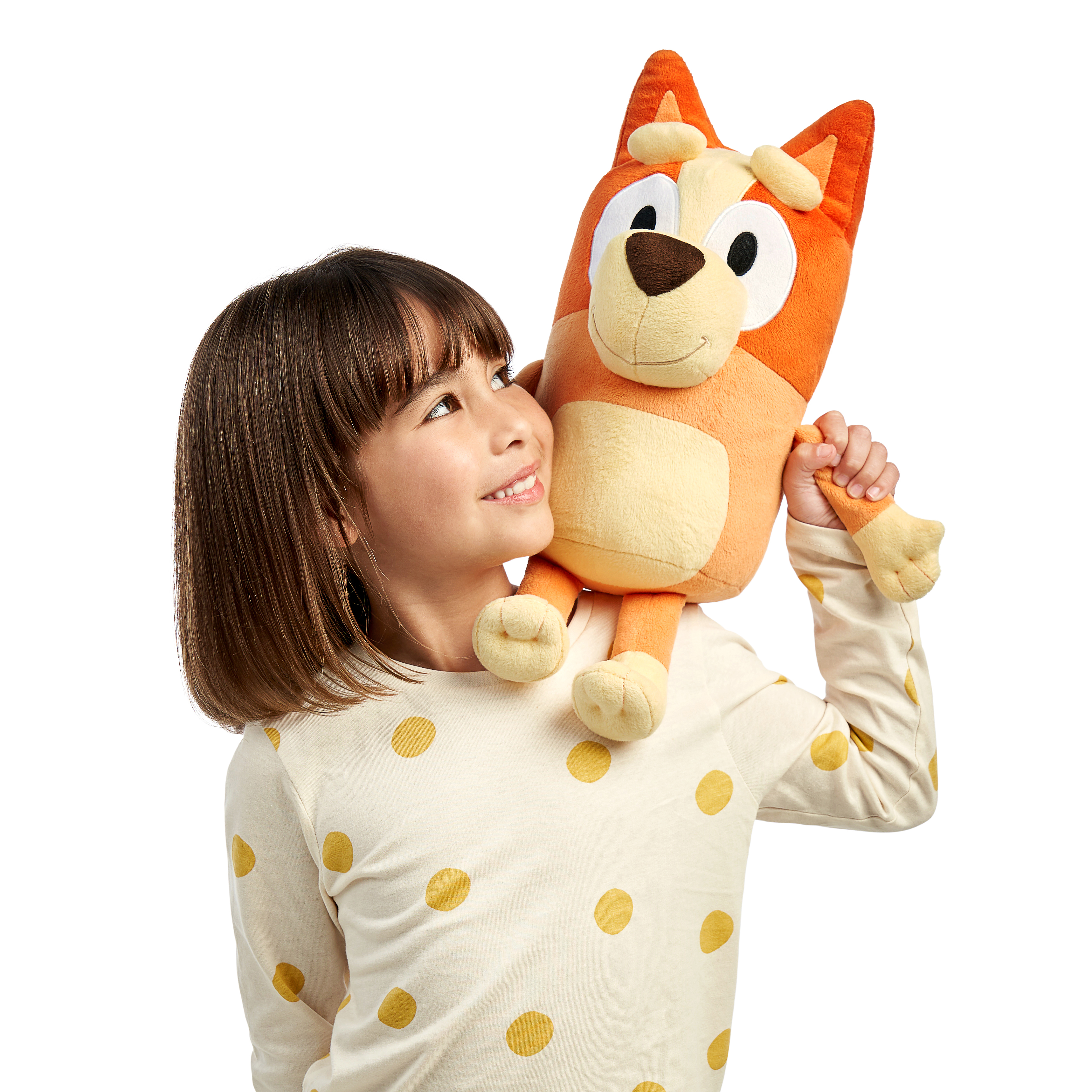 Młoda dziewczyna obejmująca dużą pomarańczowo-żółtą pluszową zabawkę Bluey, uśmiechając się do niej.