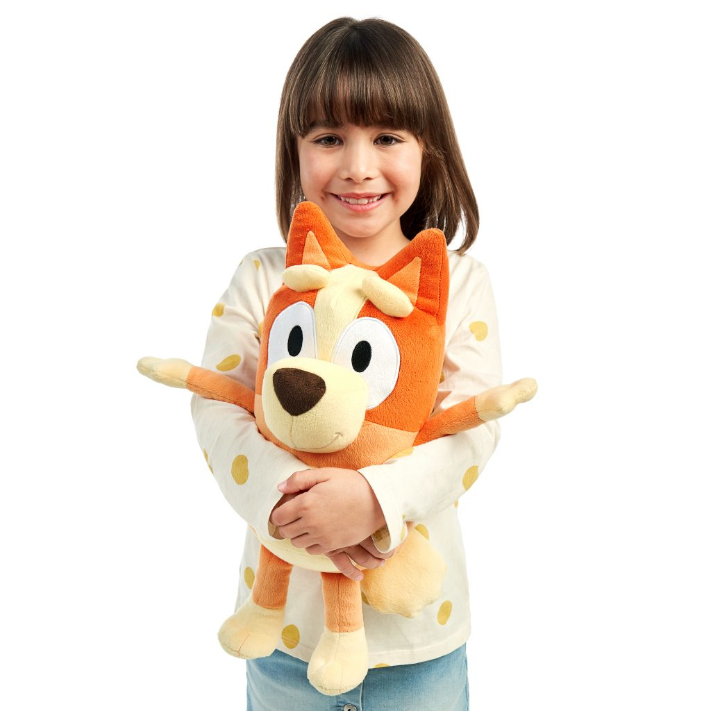 Dziewczyna trzymająca pomarańczowo-białą pluszową zabawkę psa.