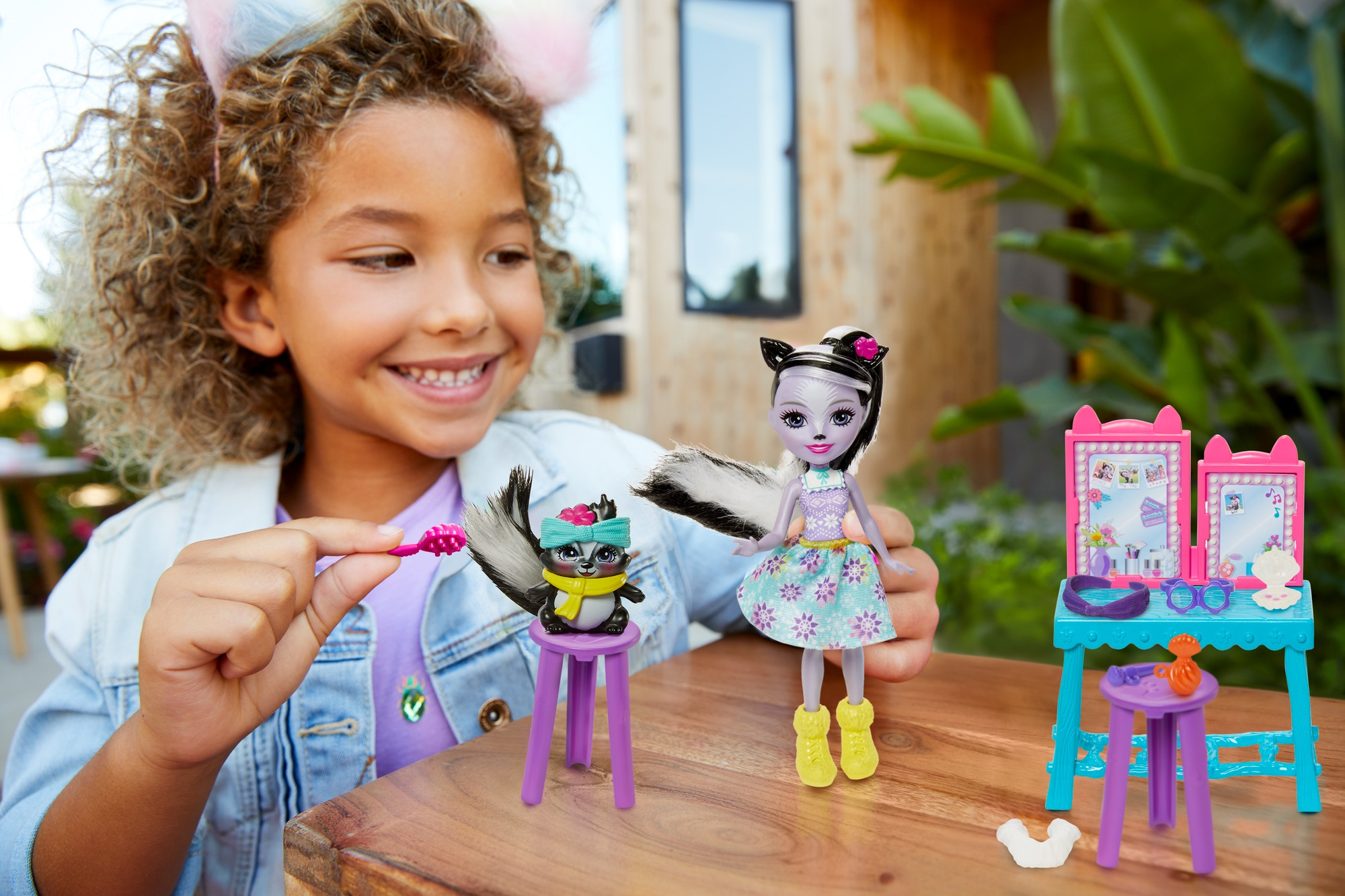 Mädchen spielt mit einem Puppenset. Die Puppe wird von einem Mädchen gepflegt. Grüner Hintergrund.