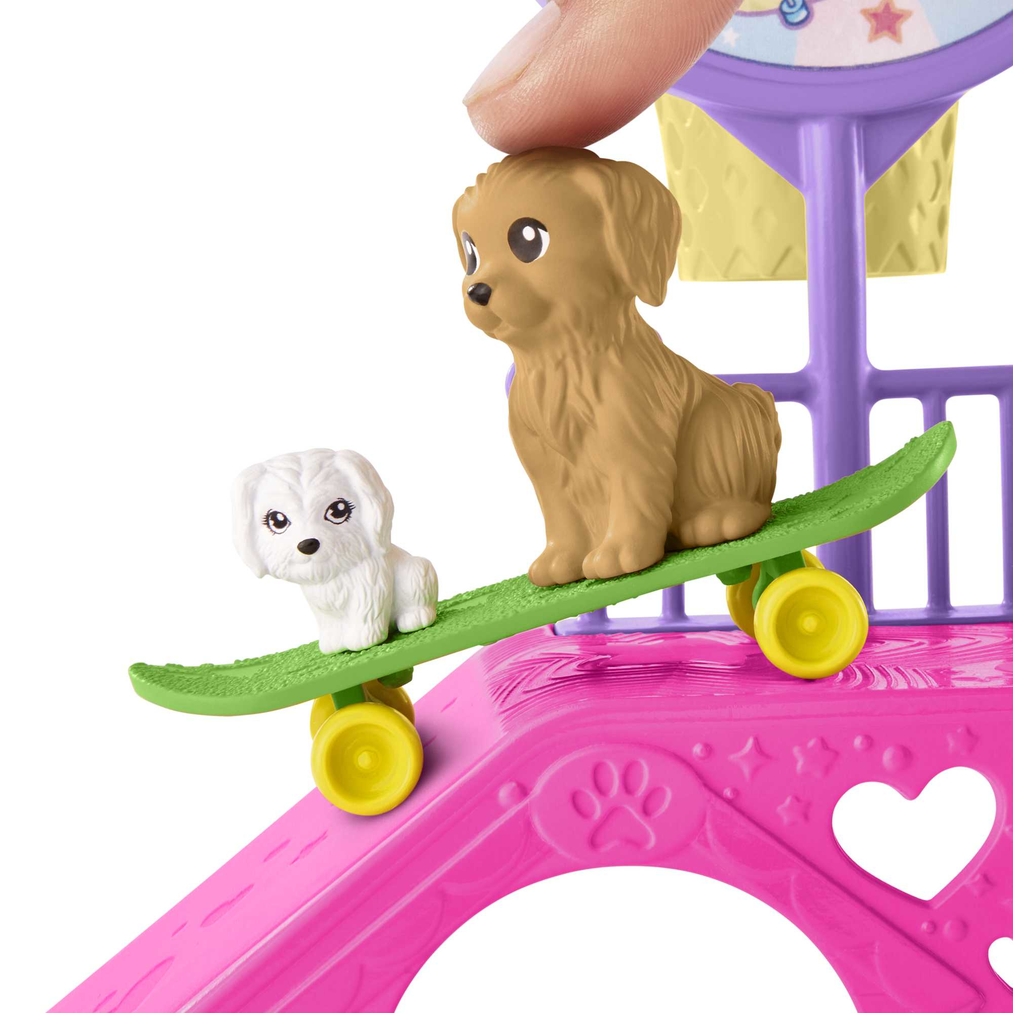 Zwei Spielzeughunde auf einem Skateboard auf einer rosa Spielstruktur. Weißer Hintergrund.