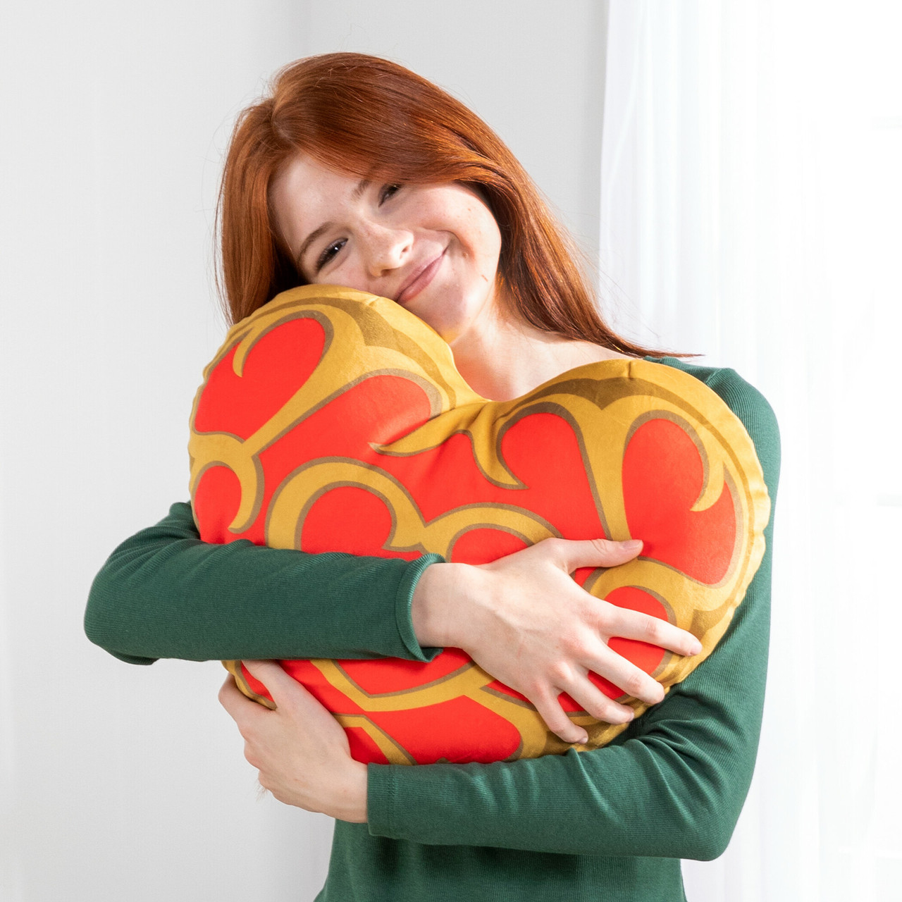 Kobieta obejmująca poduszkę w kształcie serca. Białe tło.