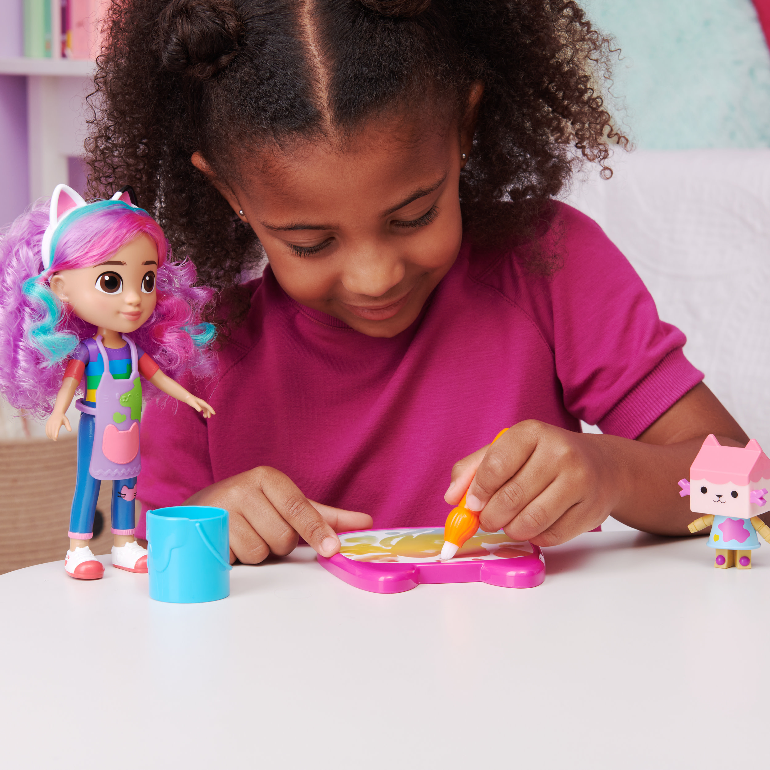 Dziewczyna rysująca z lalką i zabawką do rysowania na białym stole.