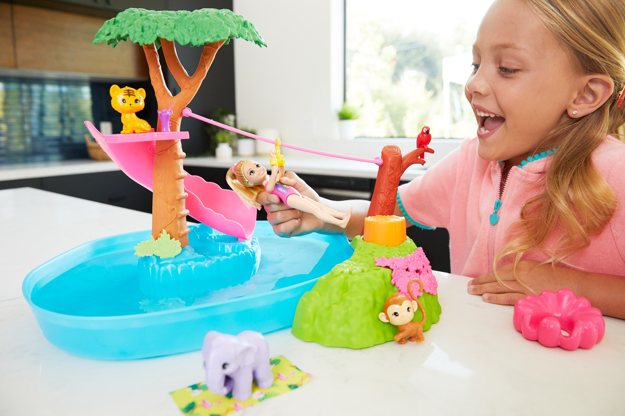 Mädchen spielt mit Barbie-Spielset mit Wasser, Rutsche und Pool.