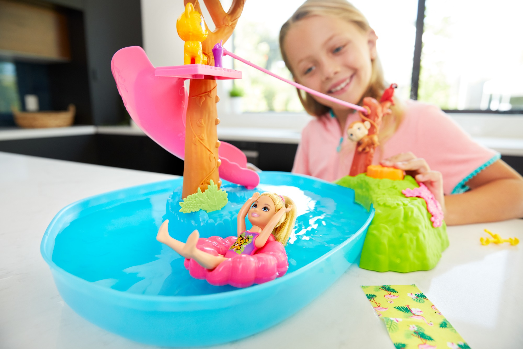 Mädchen spielt mit Barbie-Spielset mit Wasser, Rutsche und Pool.